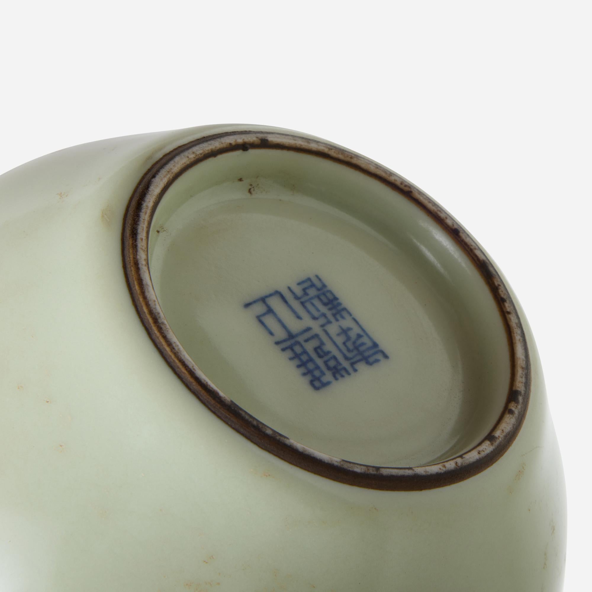 Celadon-Glasur Langhalsflasche Vase

Vase aus Porzellan mit zartgelber Glasur, bauchigem Körper und langem, schmalem Hals. Der Sockel ist in der Mitte unglasiert, und ein dunkelblaues Unterglasurzeichen ist vorhanden. Die Oberfläche weist leichte
