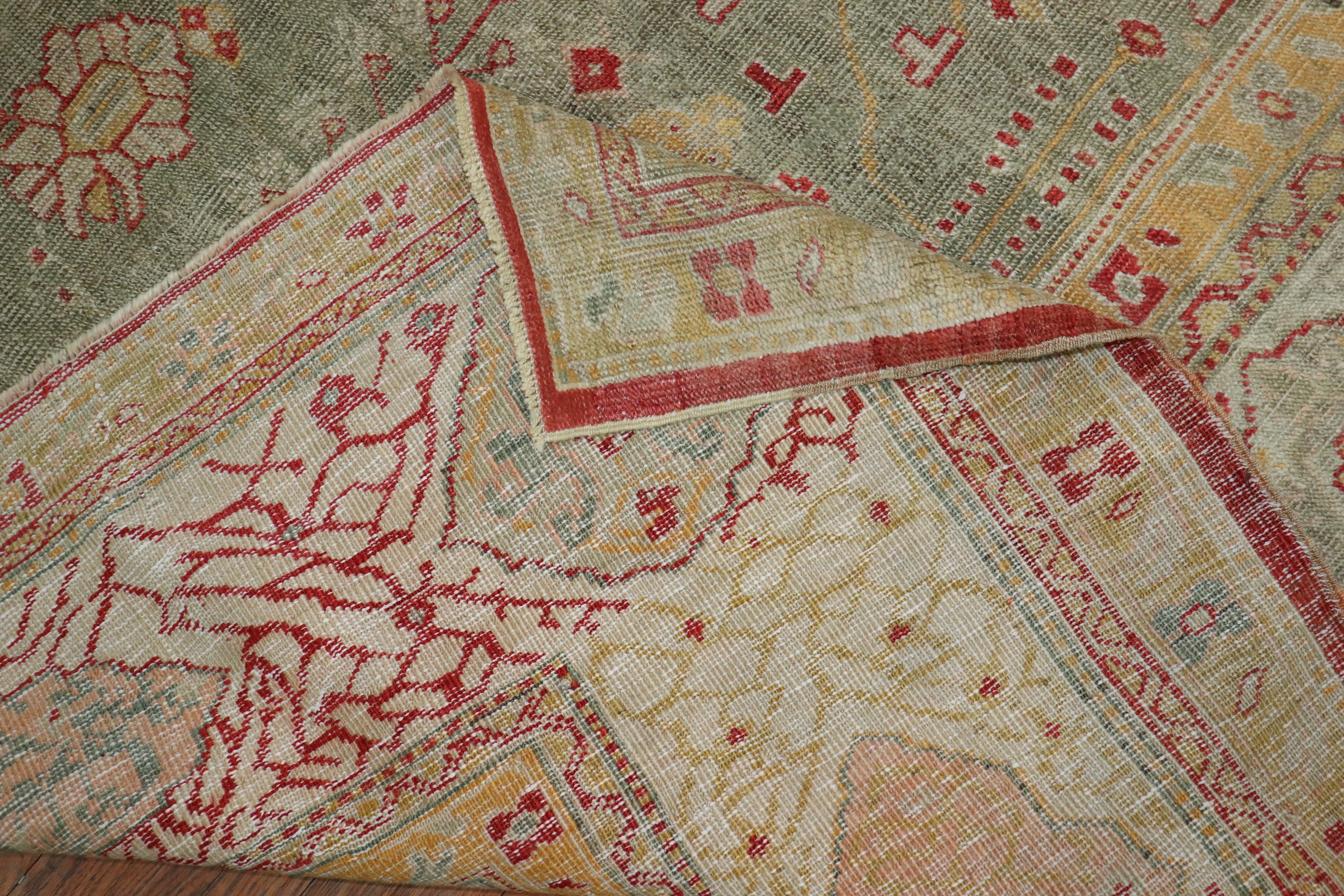 Authentique tapis turc Oushak ancien de la fin du XIXe siècle, fait à la main, avec un champ vert céladon, un médaillon central et une bordure ivoire. Des accents de jaune clair et de rouge orangé.

Mesures : 12'10