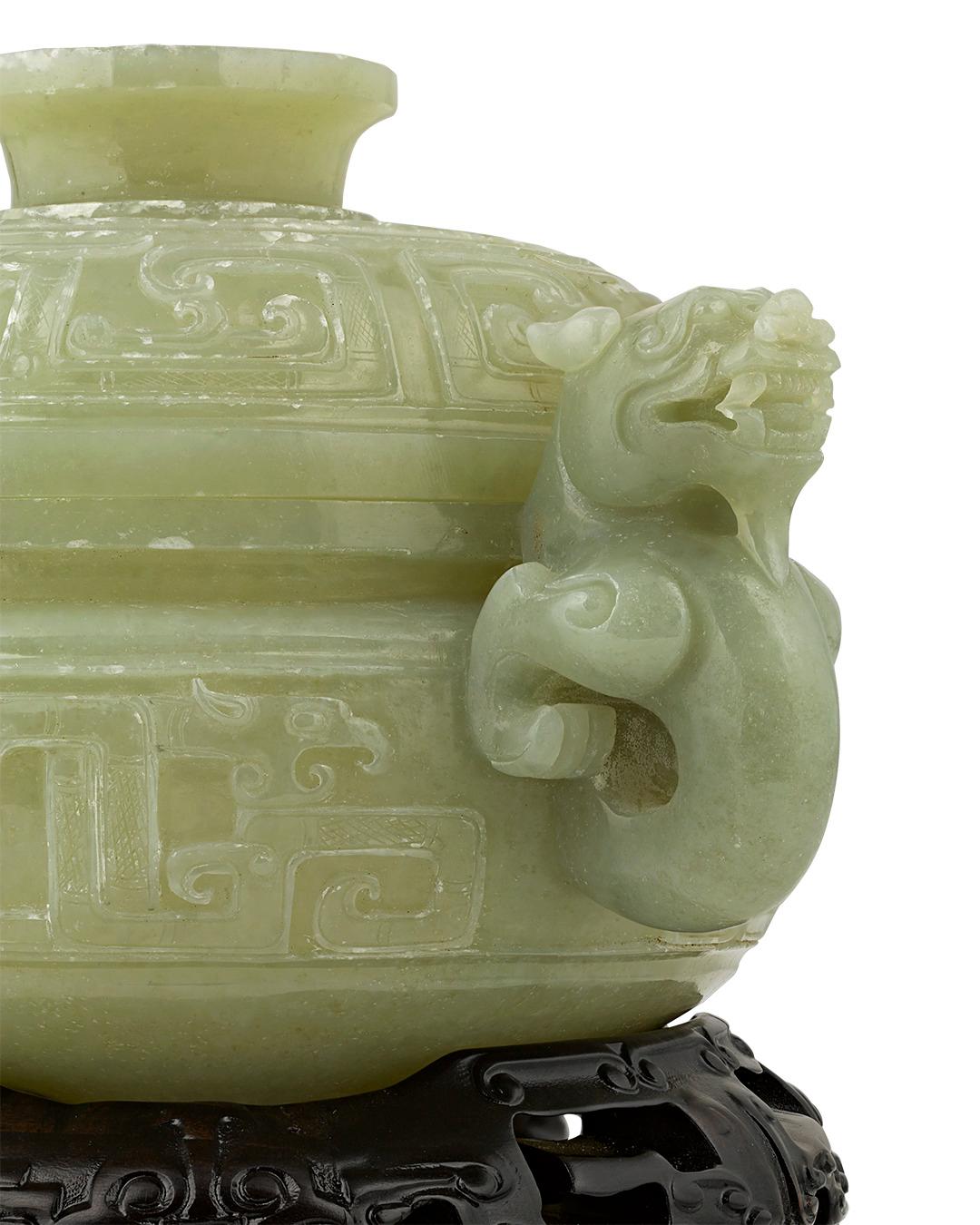 A pair of dragons serve as the handles of this exceptional Chinese covered bowl. The intricate piece is crafted from a rare type of pale green jade known as 