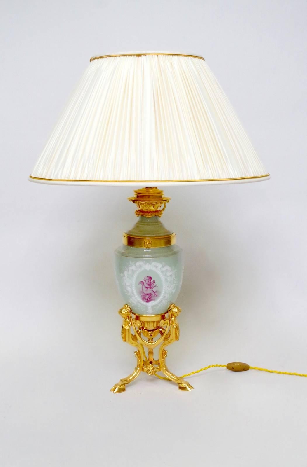 Louis XVI style amphorae shape Celadon porcelain lamp decorated with two medallions representing allegories of the music and the drawing, adorned with flowers garlands.
Mount in chiselled and gilt bronze, lamp resting on a tripod Stand decorated