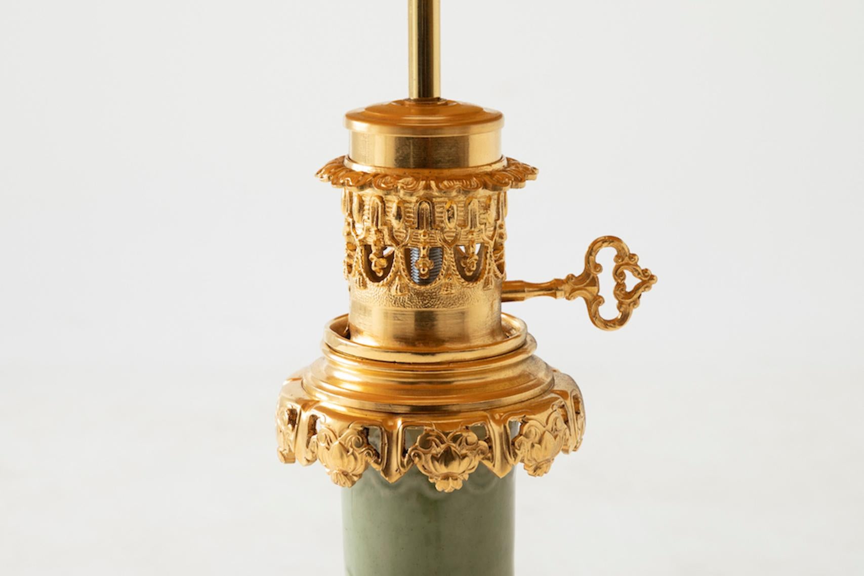 Celadon porcelain lamp, bottle shaped, mounted with chiselled and gilt bronze on a circular openwork base adorned with swirls, leaves and cartouches. Higher part of the mount is also openwork and decorated of small cartouches, trimming and a