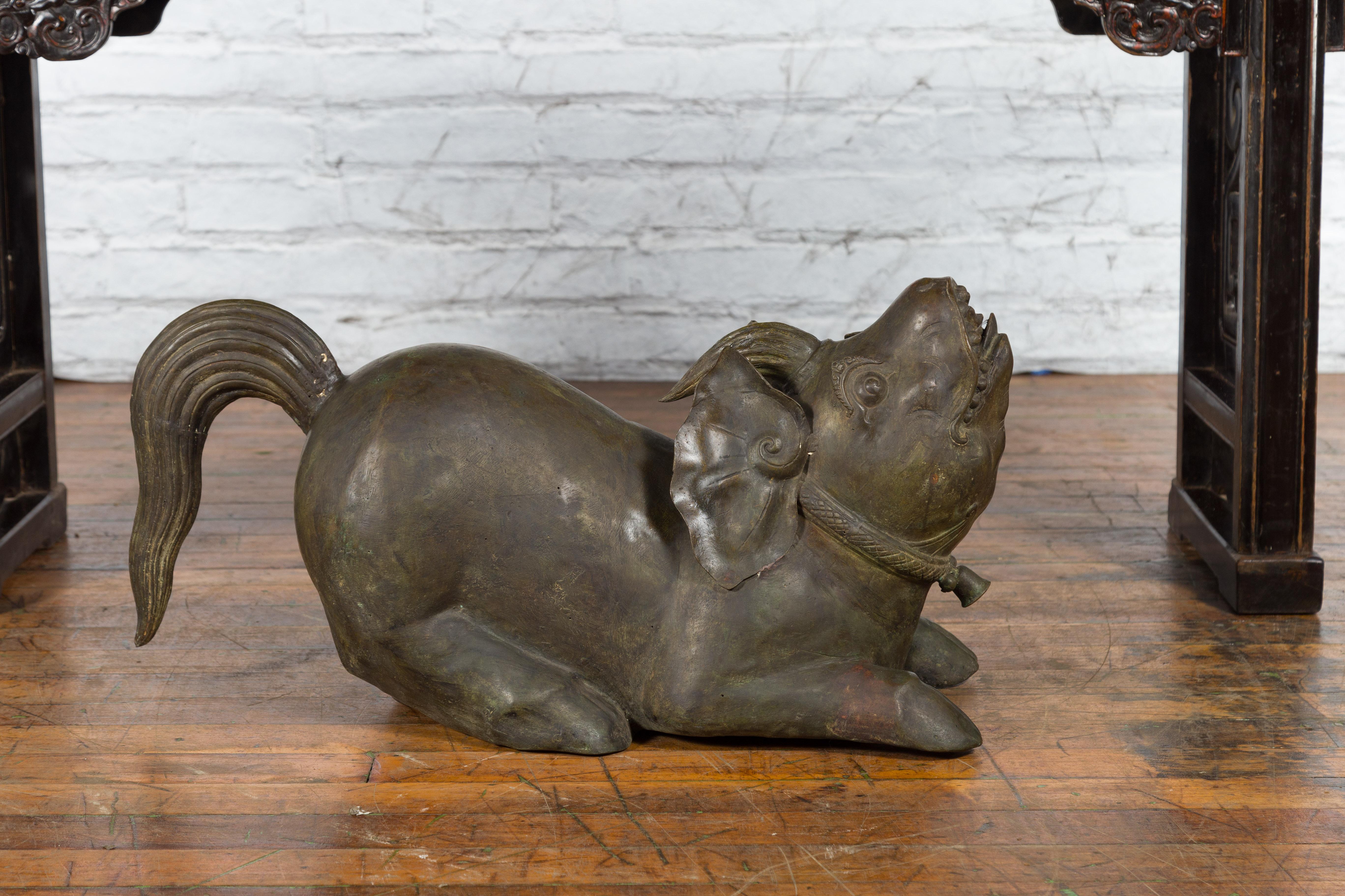 Eine indonesische handgefertigte Metallskulptur von der Insel Celebes, die ein Tempelmonster mit Schweineohren und -beinen, Horn, Schwanz und einer Glocke um den Hals darstellt. Diese handgefertigte Metallskulptur wurde auf der indonesischen Insel