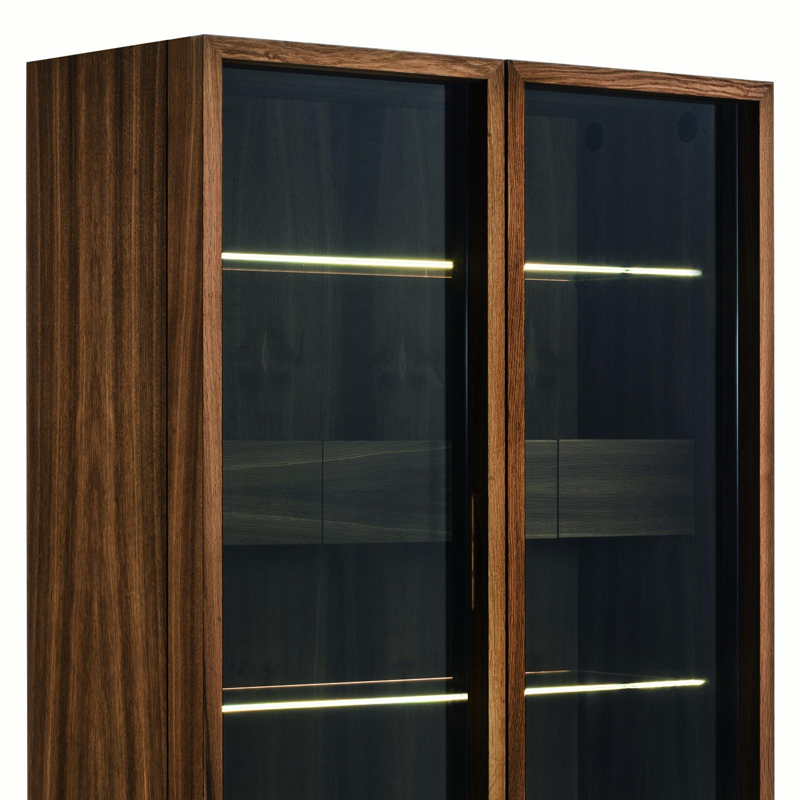 Wardrobe Celeste with all structure in solid walnut wood, with 180° openable
glass doors with a wooden frame. With iron base. Inside is lighted with LED strips 
along the inner sides which are activated automatically via touch sensors by the