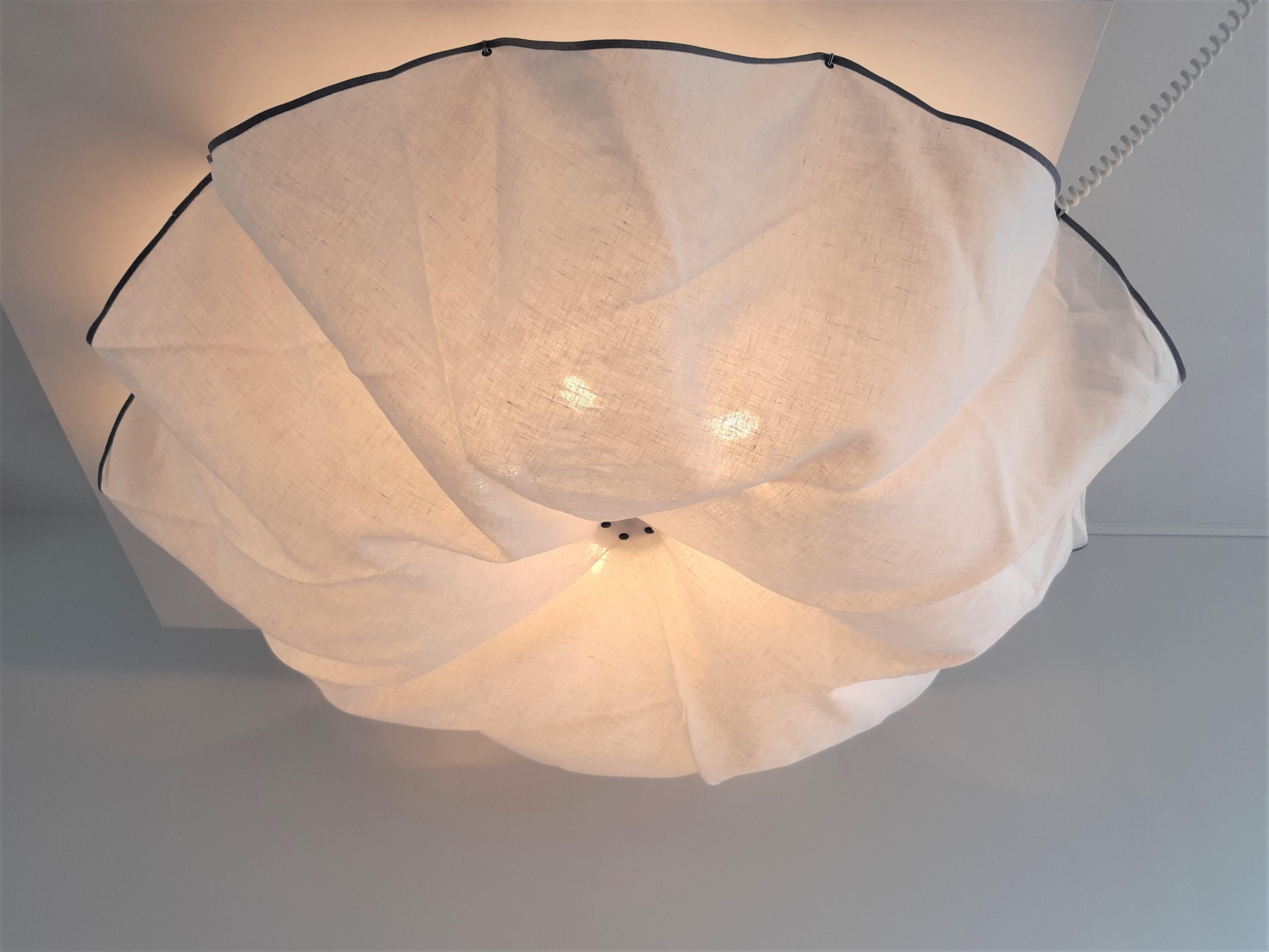 This stunning ceiling lamp, model 'Celestia' was designed in the 1980's by Tobia Scarpa for Flos in Italy. It has a linen fabric hanging diffuser containing 11 pins, that is attachted with 5 press studs on a metal frame surrounded by 5 light