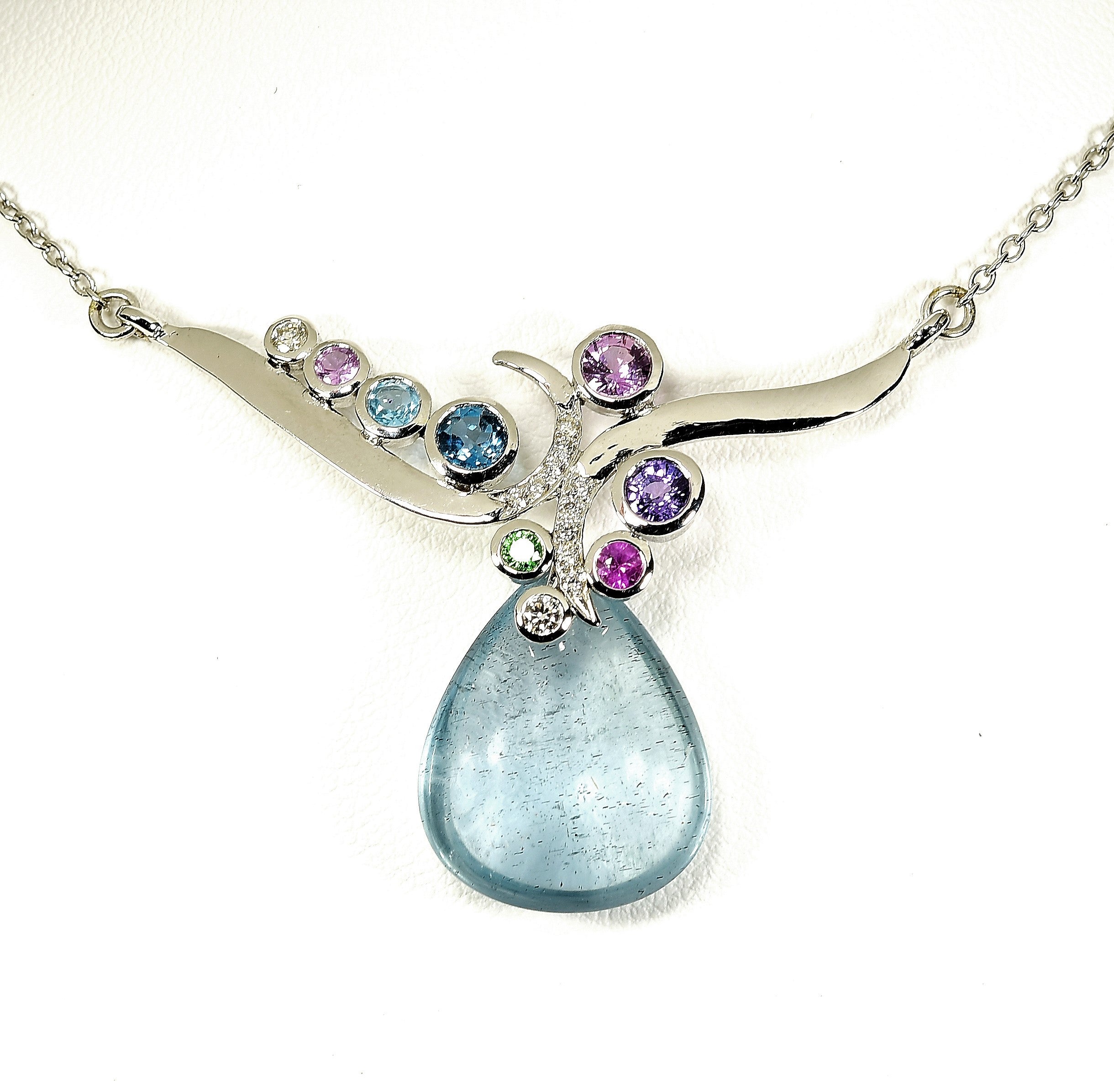 A luminous 13.66-carat polished aquamarine drop forms the centerpiece of this elegant celestial-inspired pendant. The gem gently dangles from behind two graceful swirls of 14K white gold, accented by tiny pavé-set diamonds and an array of bezel-set