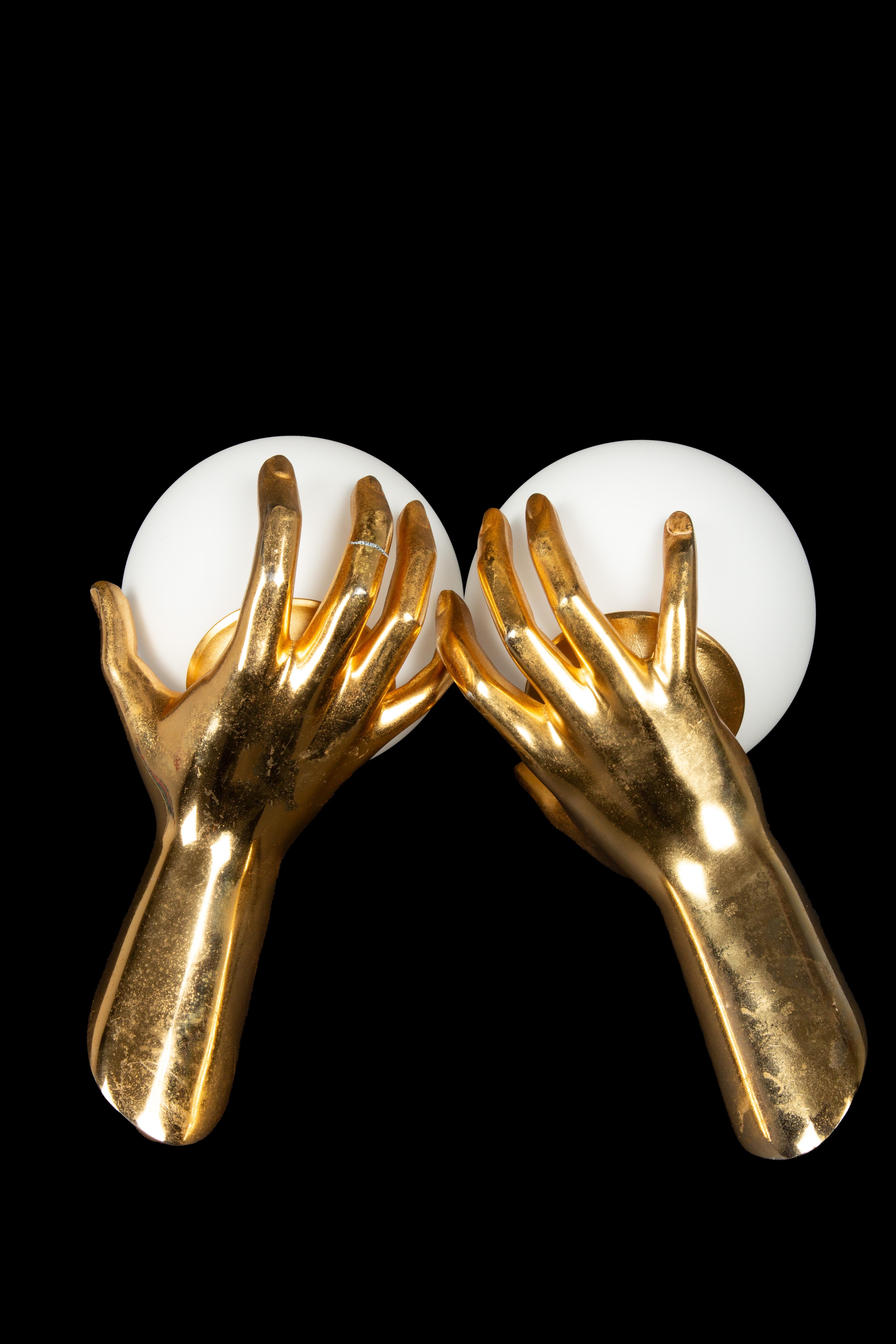 Exquisite and exceedingly rare pair of gilt bronze hand sconces crafted by Maison Arlus. These remarkable pieces, model number 1436, feature a captivating design depicting a finely detailed bronze hand delicately cradling a softly illuminated