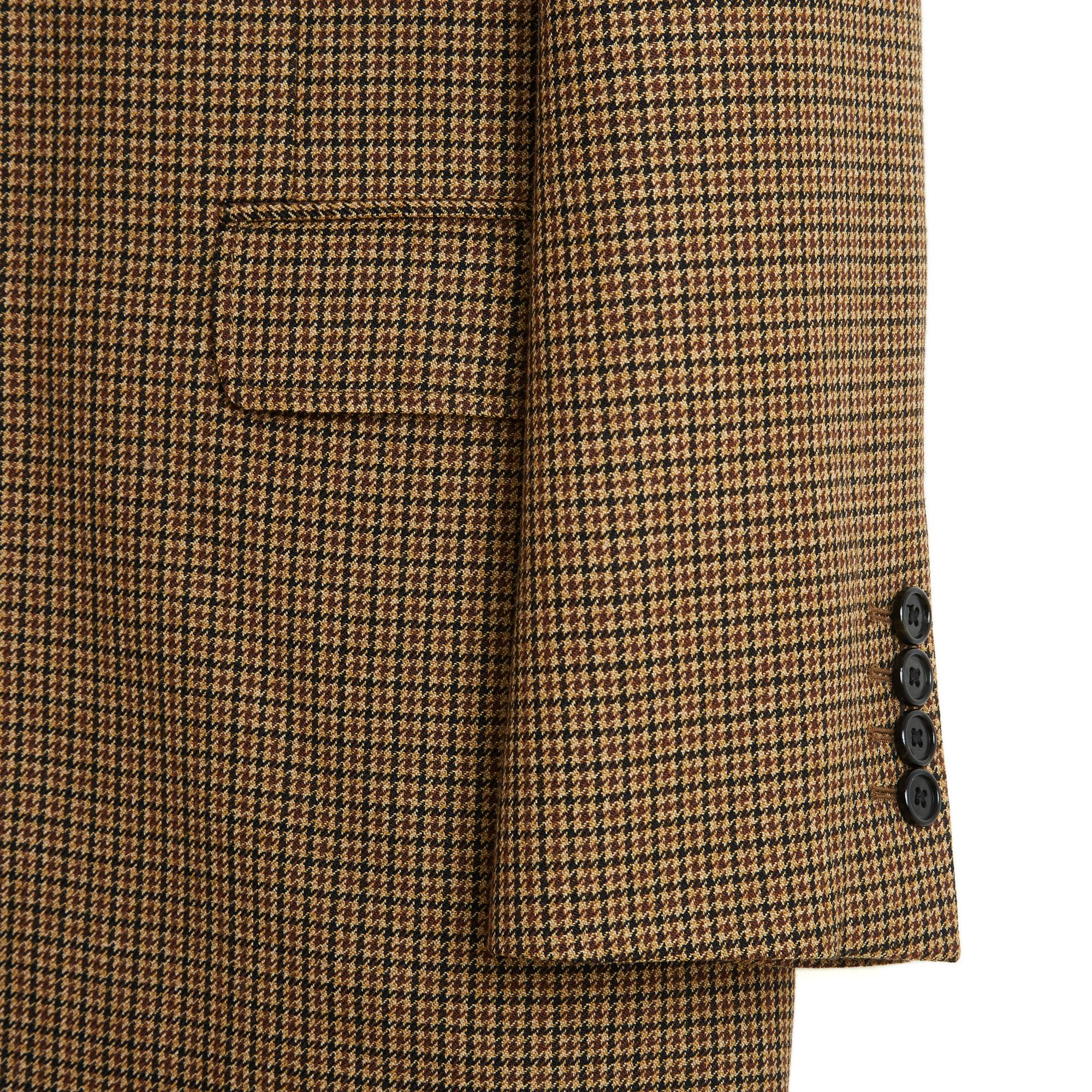 Celine Hedi Slimane, circa 2021, è un ensemble composto da giacca o blazer e pantaloni in misto lana con motivi scozzesi nei toni del marrone. La giacca è lunga, oversize, con un colletto dentellato chiuso da un solo bottone, una tasca sul petto e