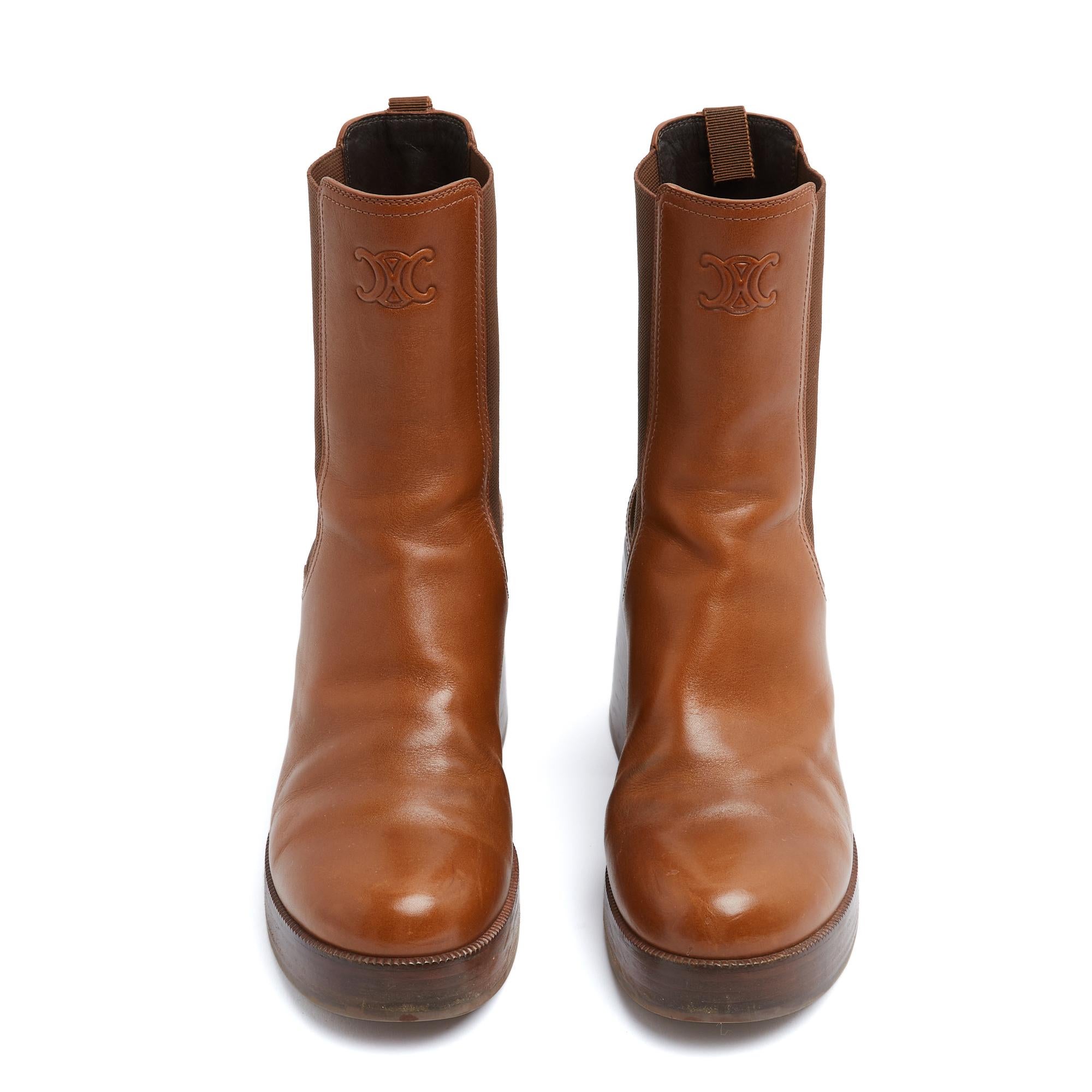 Stivaletti Celine, collezione 2025, modello Tess, forma Chelsea (comunque di ispirazione biker) in pelle color cammello con logo Triomphe sul davanti e logo Celine sul retro, elastico ai lati del gambale e nastro tira-stivali con firma Celine e