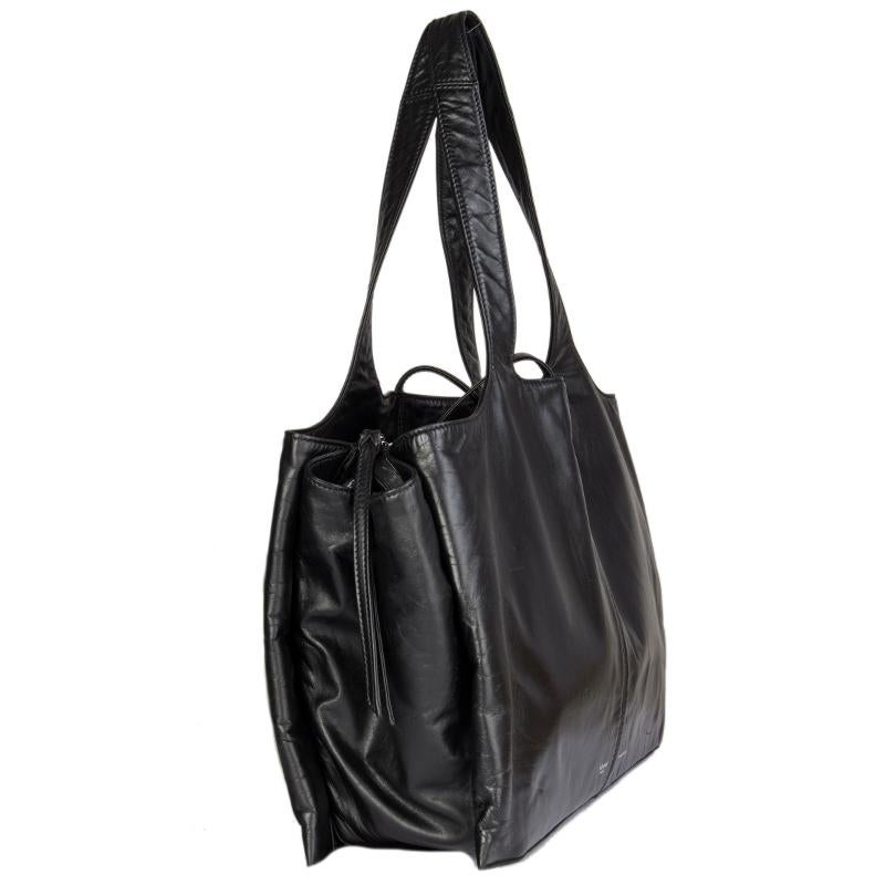 Céline 'Tri-Fold Bag' in black soft calfskin. Bag features three compartments, all drawn together with two leather laces. Lined in black calfskin. The middle part opens with a zipper on top and has two open pockets against the back. One of the outer