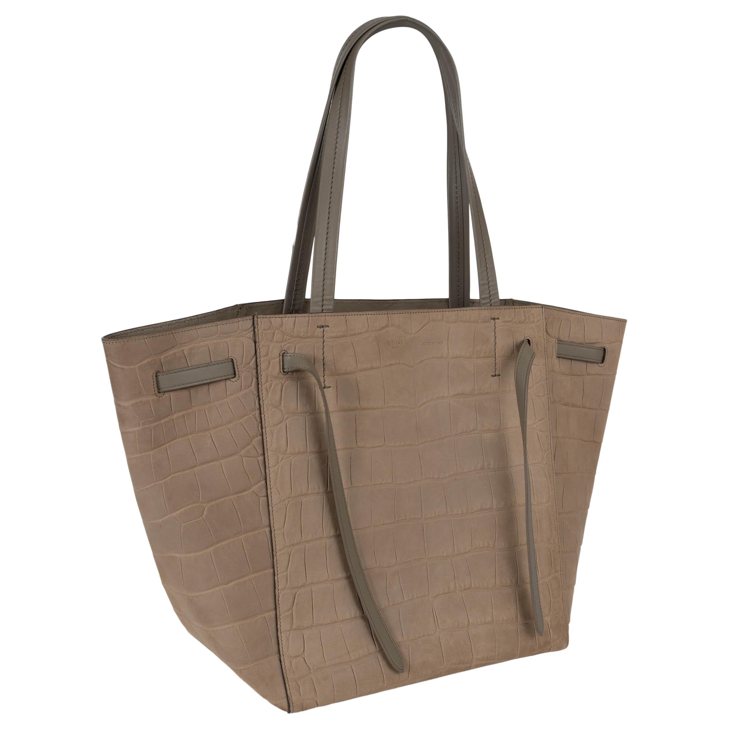 This 100% authentic Celine Cabas Phantom Small tote in beige taupe crocodile-embossed nubuck leather is the perfect everyday bag. Designed with belt straps and handles in smooth leather, it offers a sleek yet practical silhouette. The open top