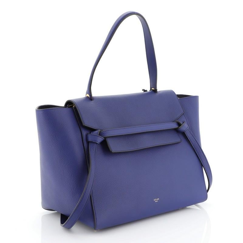 This Celine Belt Bag Grainy Leather Medium, crafted from blue grainy leather, features a looped single top handle, exterior back zip pocket, frontal flap, and aged gold-tone hardware. Its zip closure opens to a blue suede interior with slip