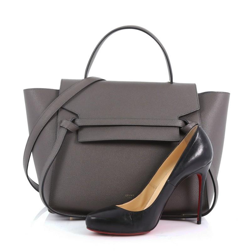 This Celine Belt Bag Grainy Leather Mini, crafted from gray grainy leather, features looped single top handle, exterior back zip pocket and gold-tone hardware. Its zip closure opens to a gray suede interior. **Note: Shoe photographed is used as a