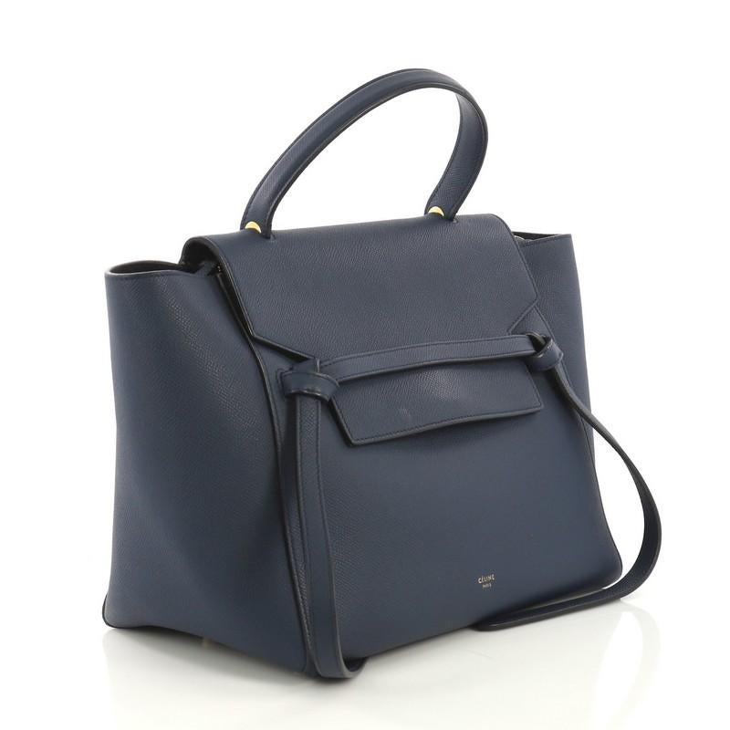 This Celine Belt Bag Textured Leather Mini, crafted from blue leather, features single looped top handle, top flap slide closure, exterior back zip pocket, and aged gold-tone hardware. Its top zip closure opens to a blue suede and leather interior