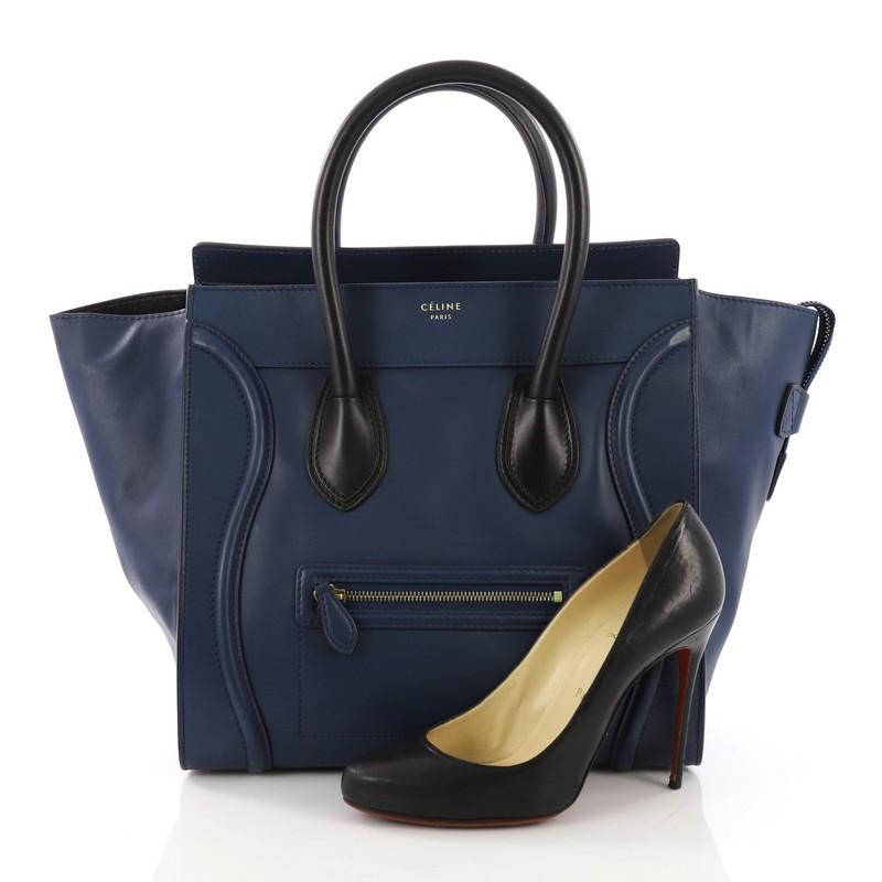 This Celine Bicolor Luggage Handbag Leather Mini, crafted in blue leather, features a front zip pocket, dual rolled leather handles, protective base studs, and gold-tone hardware. Its top zip closure opens to a black leather interior with zip pocket
