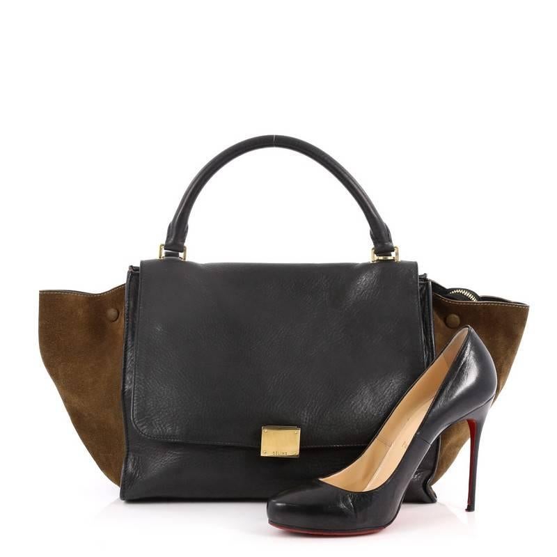 This authentic Celine Bicolor Trapeze Leather Medium is a modern minimalist design with a playful twist in an array of subdued colors. Crafted from black leather with olive green suede side wings, this classic satchel features rolled top handle,