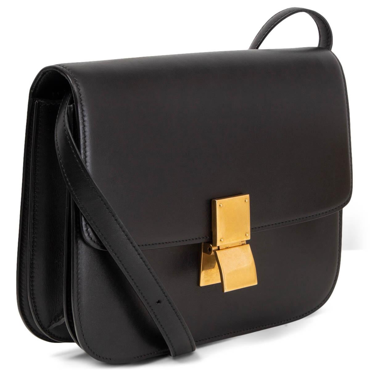 100% authentic Céline Medium Classic shoulder bag in black box calfskin. Opens with a gold-tone push-lock on the front. The inside is divided into two compartments with two open pockets against the front and a zipper pocket against the back. Lined