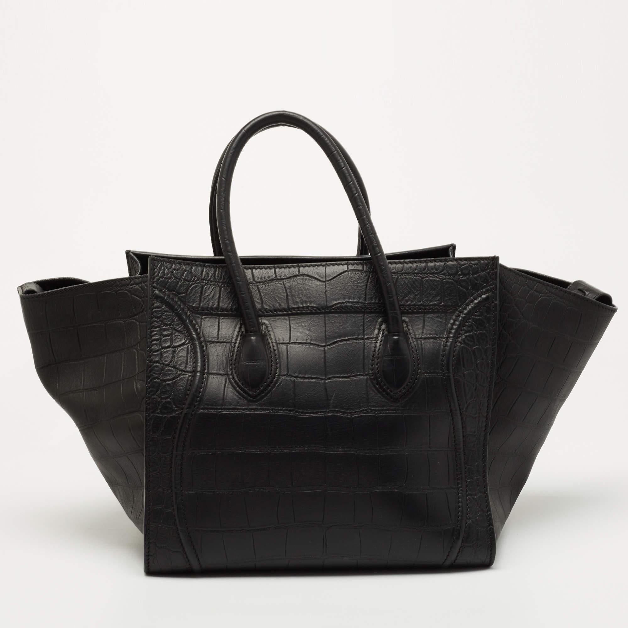 Celine released the Phantom as a newer version of their successful Luggage model. Unlike the Luggage toes, the Phantom has an open top, wider wingspans, and a braided zipper pull. We have here the one in croc-embossed leather. It has two top