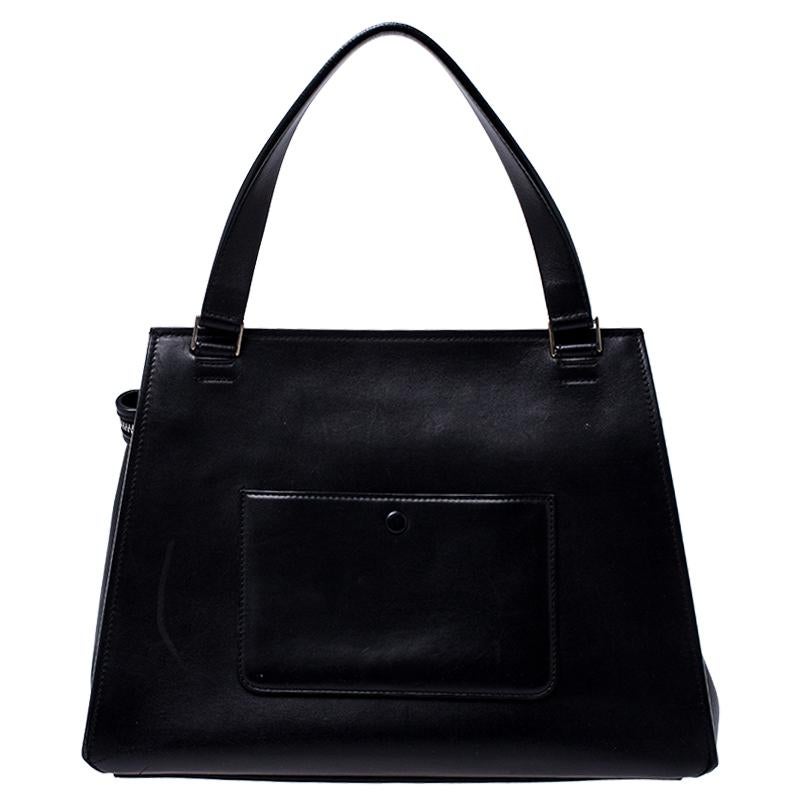 This Celine Edge bag is not only visually magnificent but also functional. It has been crafted from leather and styled with a silhouette that is classy and posh. The black and grey bag has a top handle and a top zipper that reveals a spacious