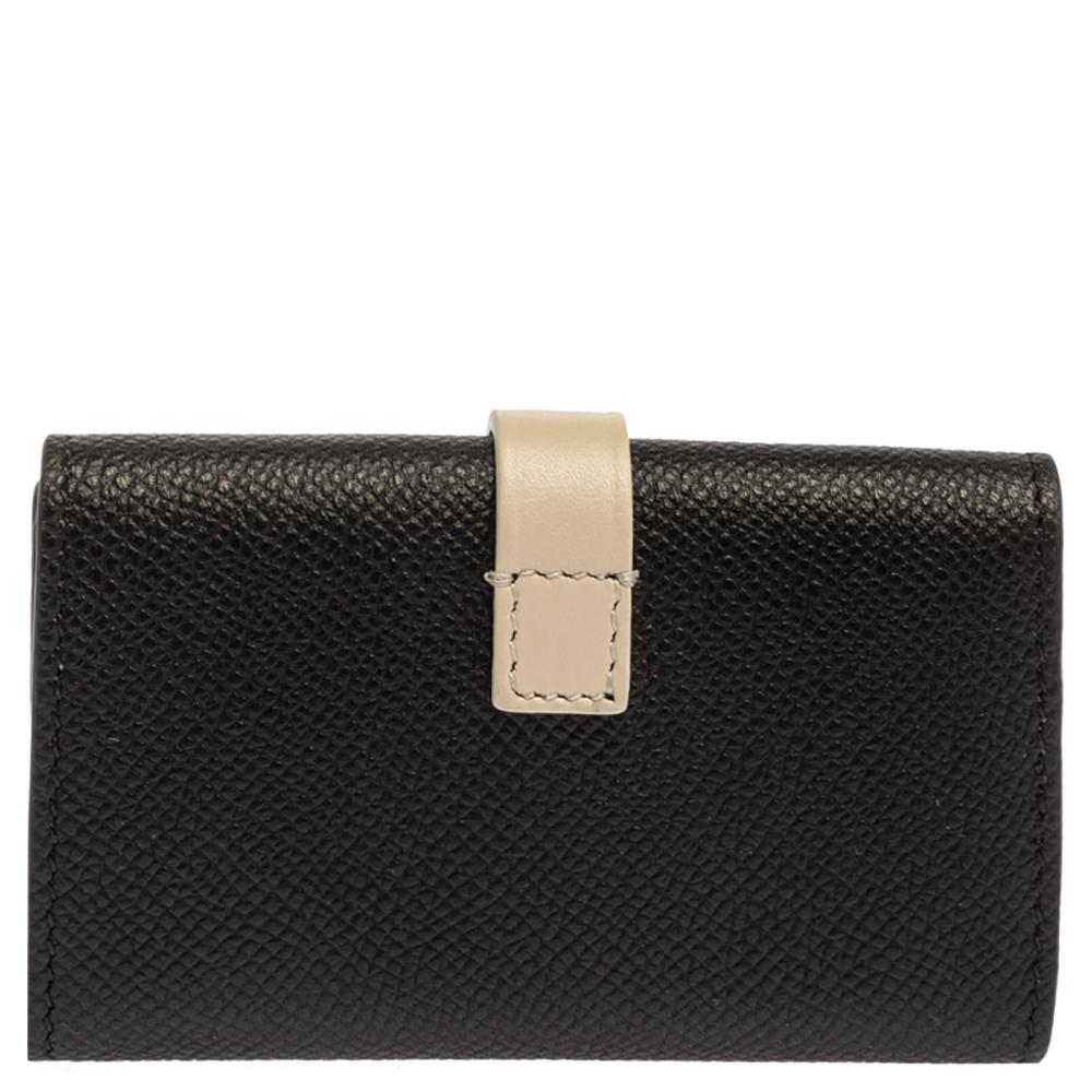 Simple and polished with a luxe edge, this key case stands out with its structured shape. Made from luxurious grained leather in black and ivory shades, it is complete with a strap snap closure and silver-tone hardware.

Includes:Original Box,