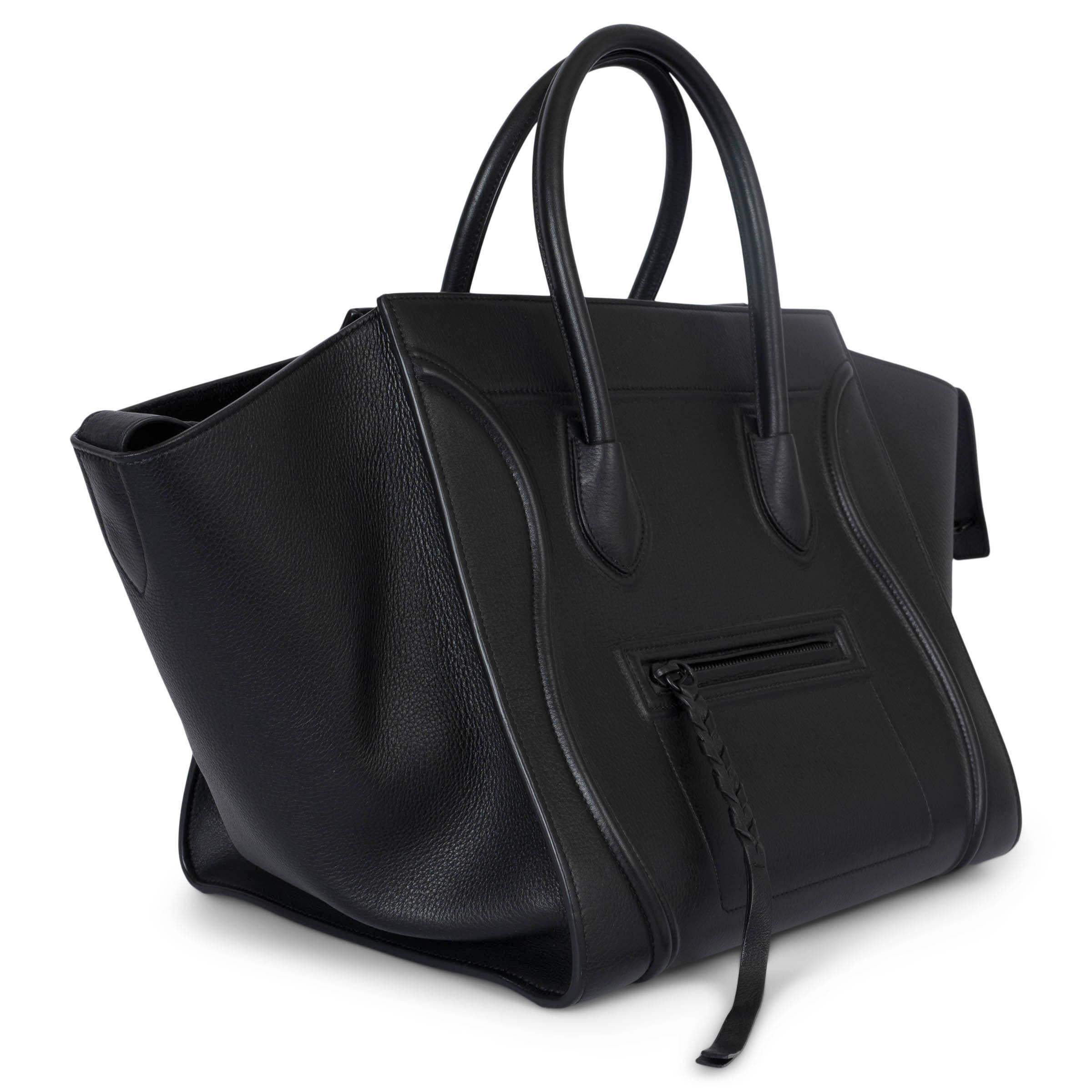 100% authentic Céline Medium Phantom Luggage tote bag in medium black grained calfskin featuring a small zip front pocket. Lined in suede with one zipper pocket against the back. Has been carried and is in excellent condition. Comes with dust bag.