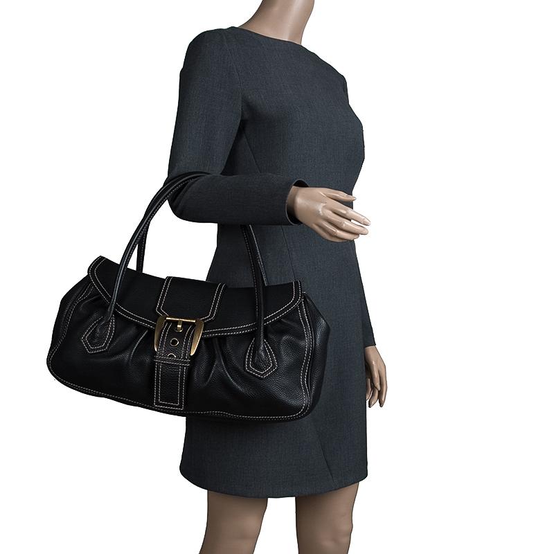 This black satchel from Celine is an everyday style! Crafted in quality leather, the bag features a gold tone buckle fastening closure at the flap belt. The over sized dual rolled handles are perfect to tote at work. The soft suede interior offers a