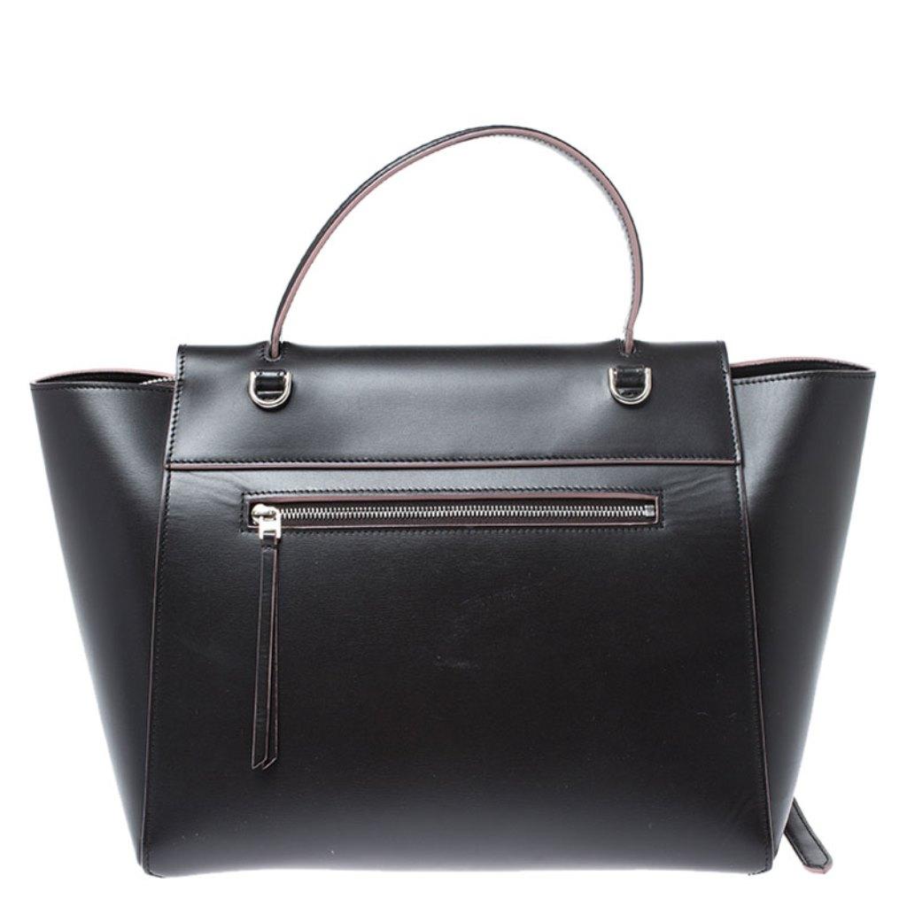 This Celine flap bag is a timeless creation that will bever go out of style. Crafted from leather, it comes in a lovely shade of black. It is equipped with a top handle, a front flap that opens to reveal a spacious leather interior with side pockets