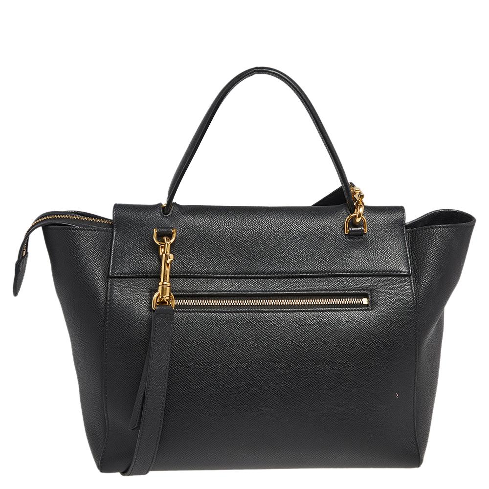 Bags from Celine are symbols of excellent craftsmanship and timeless design. This black creation has been crafted from leather and styled with a front tuck-in flap and knotted belt details. It flaunts a single top handle and a well-spaced interior