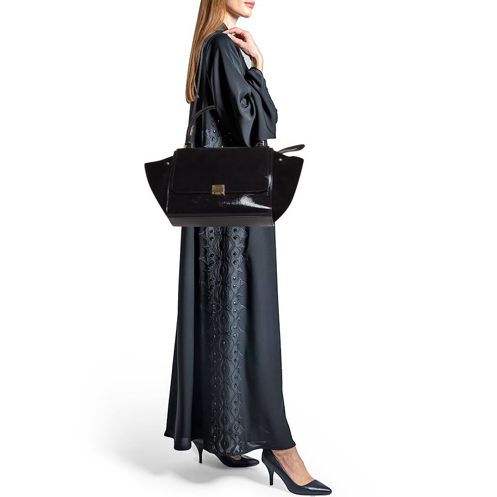 Featuring a simple yet luxurious style, this Celine bag will be a valuable addition to your closet. Crafted from patent leather and suede, it is characterized by flappy wings, gold-tone hardware, and a back zipper pocket. The front flap of this