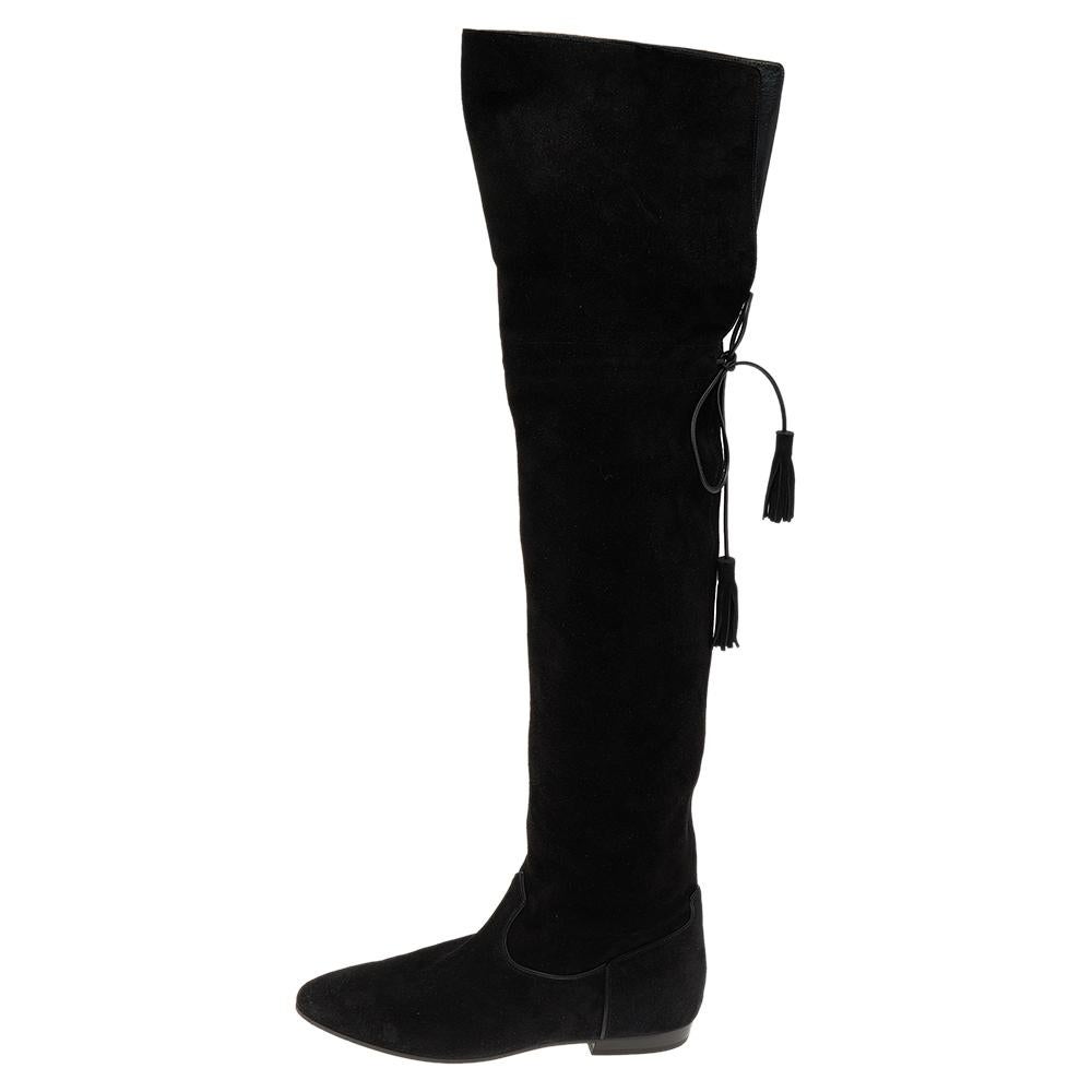 Celine never fails to design fashion-forward styles that become favorites in one's closet. These black thigh-high boots for women are a fine example. Made from suede, they feature round toes, fringe tie detailing at the back, and low