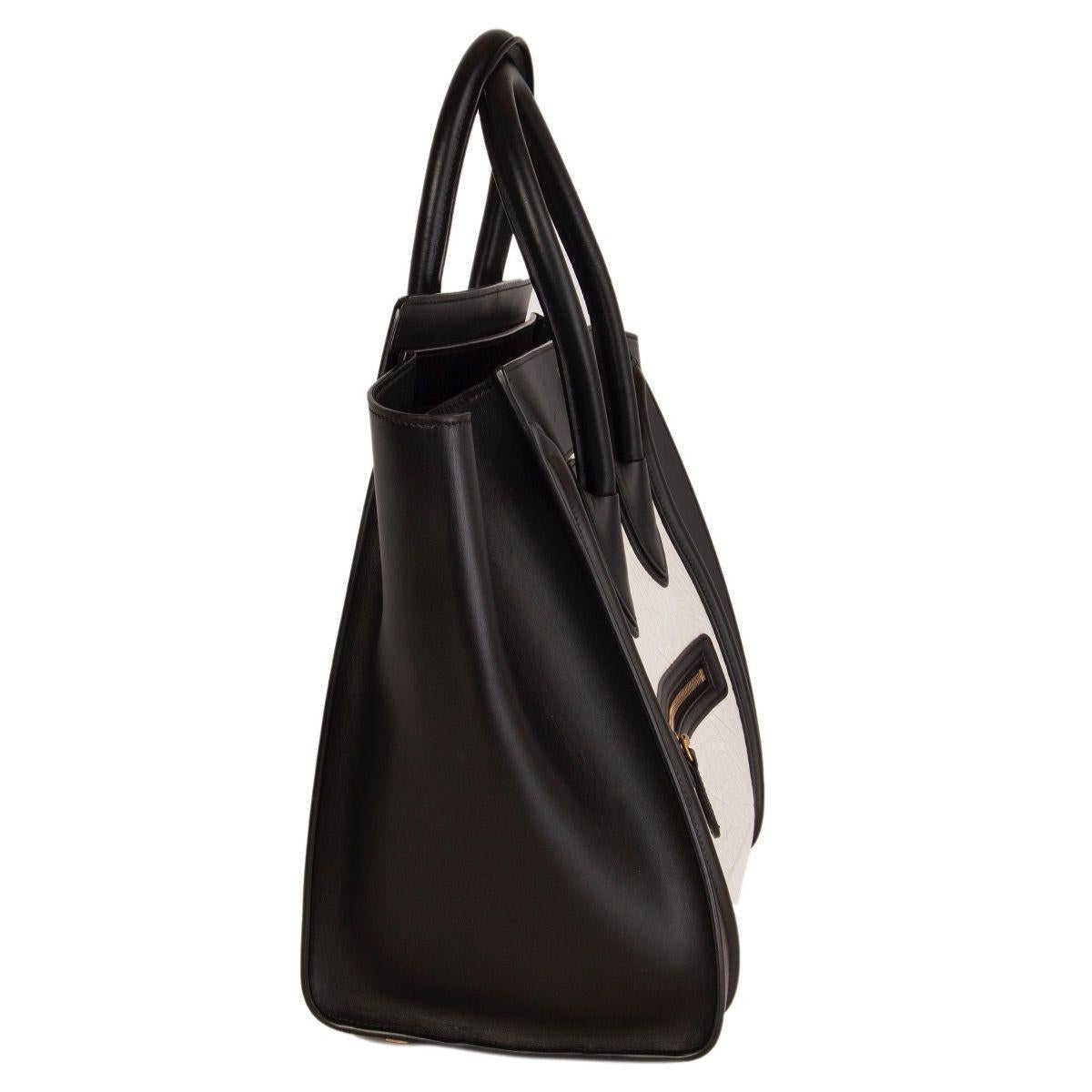 Céline 'Mini Luggage' tote in black and white large grained calfskin featuring outer zipper pocket on the front. Lined in black calfskin with one zipper pocket against the back and two open pockets against the front. Has been carried and is in