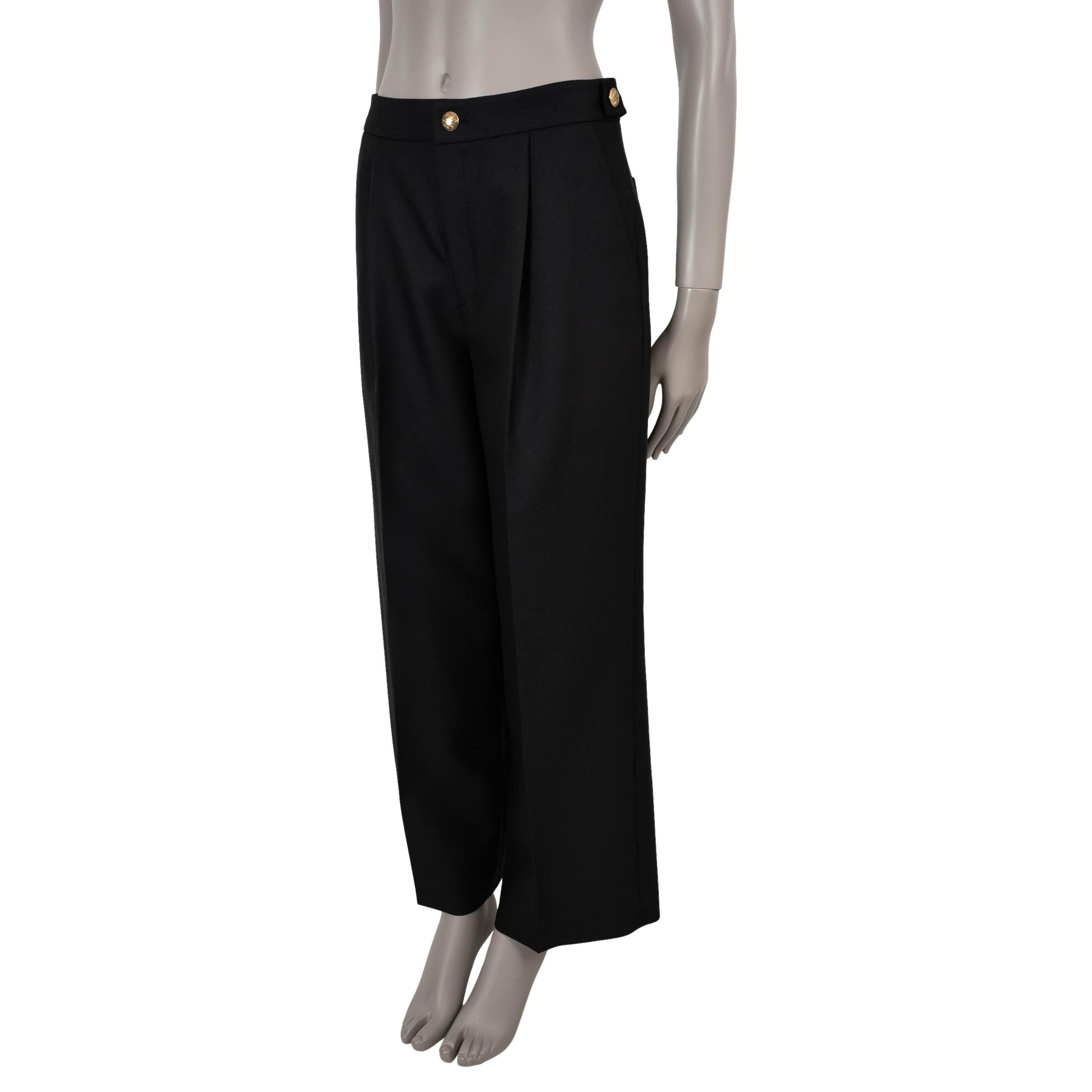 Ce pantalon Icone 100% authentique en laine noire (73%) et mohair (27%) allie un style tailleur à des détails emblématiques. Conçue avec une silhouette à taille haute et des jambes larges et évasées, elle est dotée de pattes de réglage à la taille