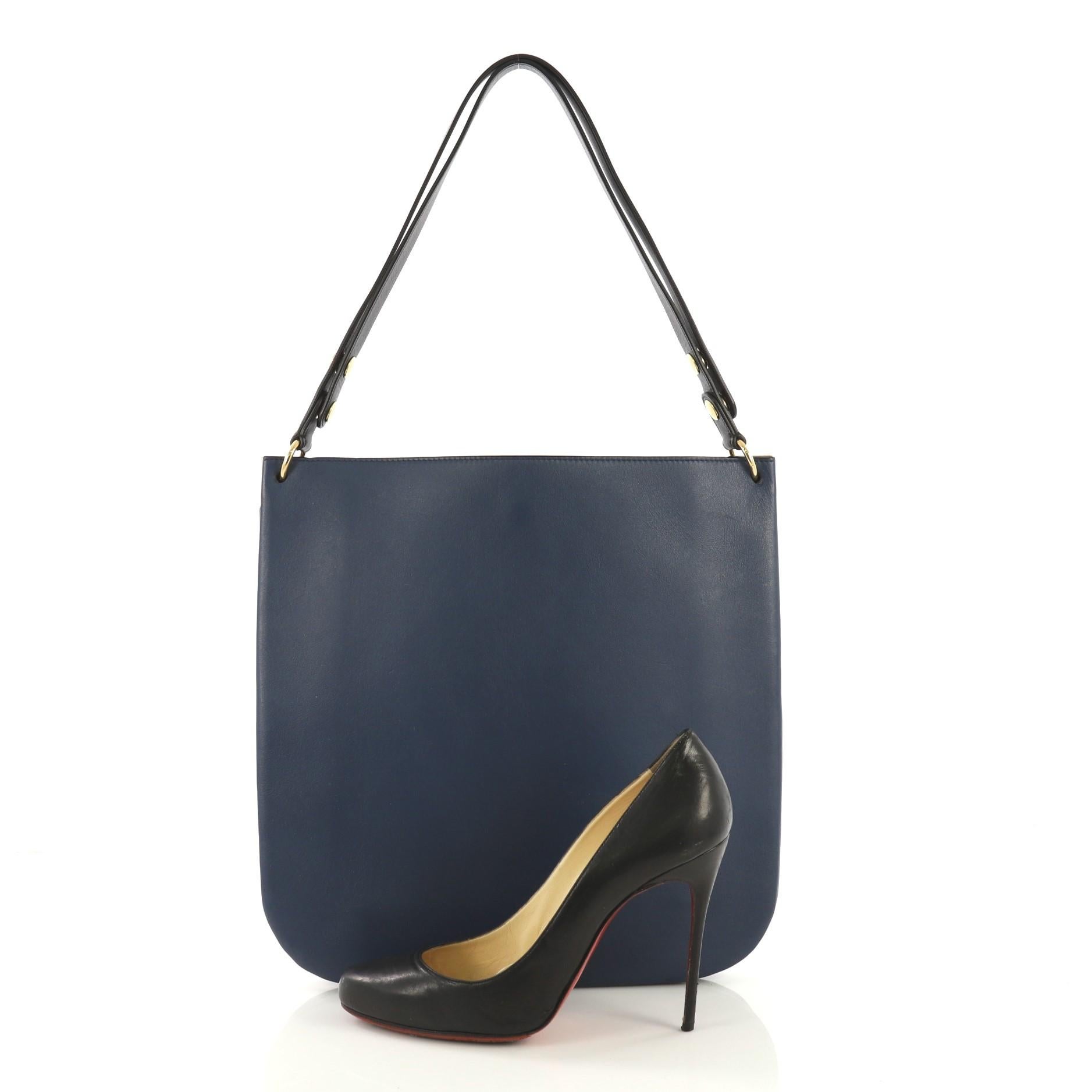 This Celine Blade Hobo Leather, crafted in blue leather, features a leather shoulder strap and gold-tone hardware. It opens to a black leather interior with three compartments, one with snap closure. **Note: Shoe photographed is used as a sizing