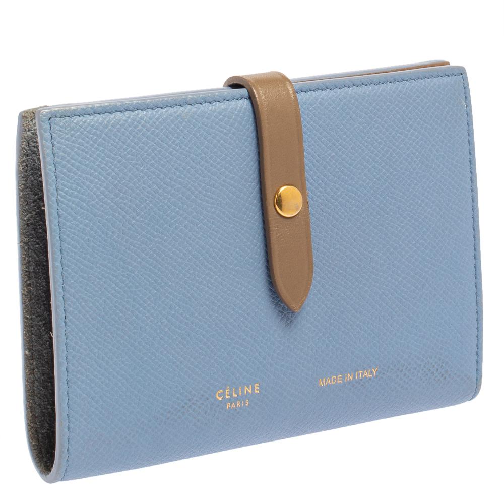 This Celine wallet is built for making a statement. Crafted from leather, it has a blue and brown exterior and a buttoned strap on the front that opens to a leather and fabric interior housing a zip pocket, slip pockets, and multiple card slots. It
