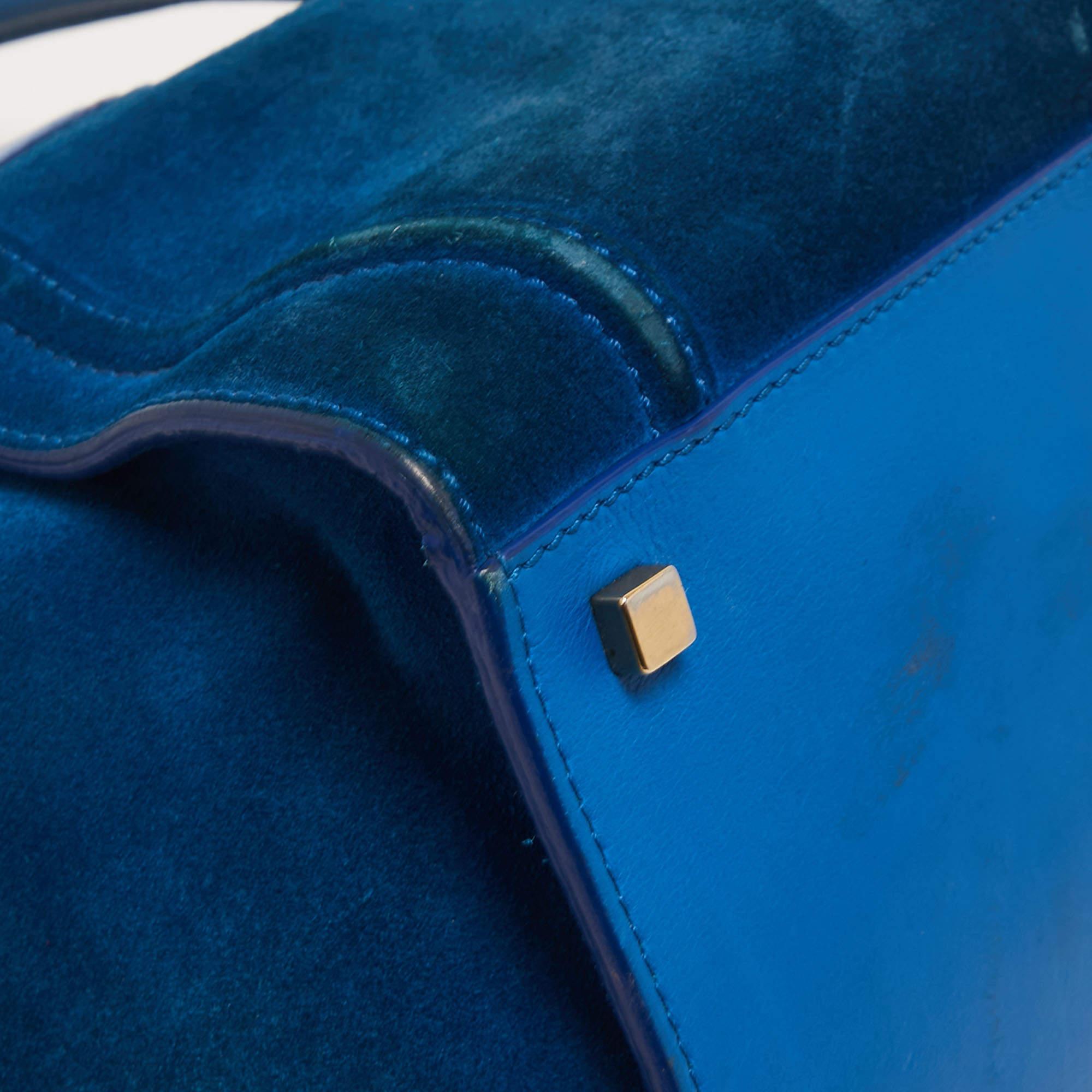 Celine released the Phantom as a newer version of their successful Luggage model. Unlike the Luggage toes, the Phantom has an open top, wider wingspans, and a braided zipper pull. We have here the one in suede. It has two top handles, a blue shade,