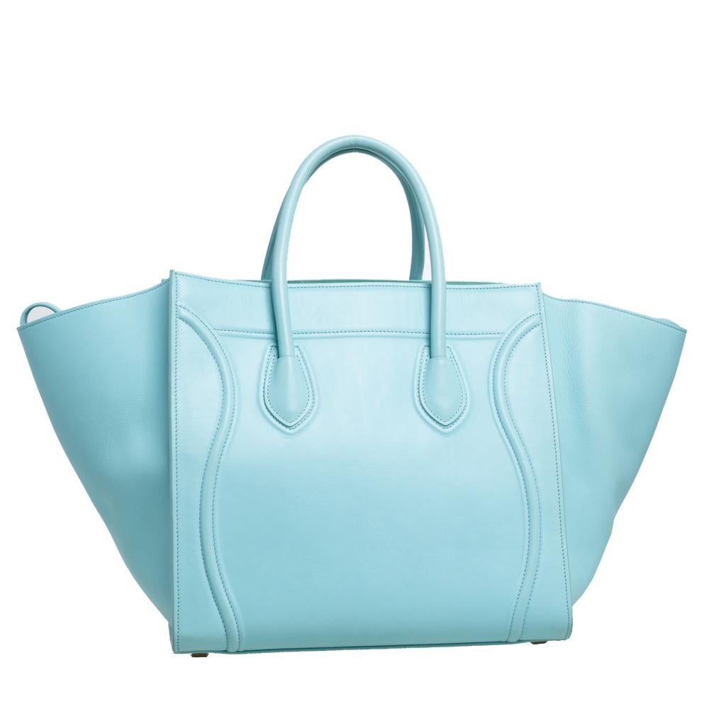 Celine released the Phantom as a newer version of their successful Luggage model. Unlike the Luggage toes, the Phantom has an open-top, wider wingspans, and a braided zipper pull. We have here the one in leather. It has two top handles, a blue