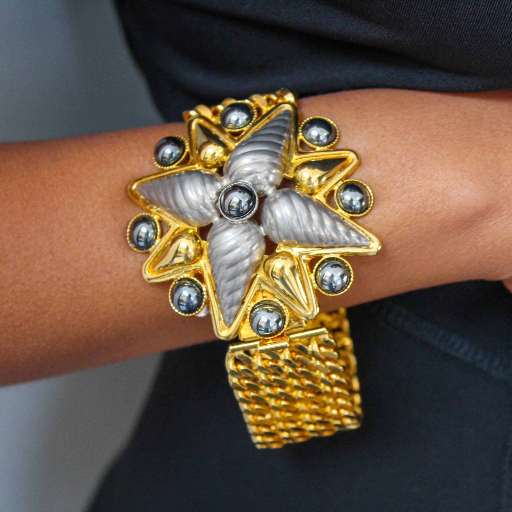 Celine 1990s Vintage Bracelet 

Show stopping bracelet from the 1990 collection. Made in Italy in 1990, this incredible bracelet is cast from gold plated metal in a mesh weave texture with a large floral centre piece set with two shade of deep grey