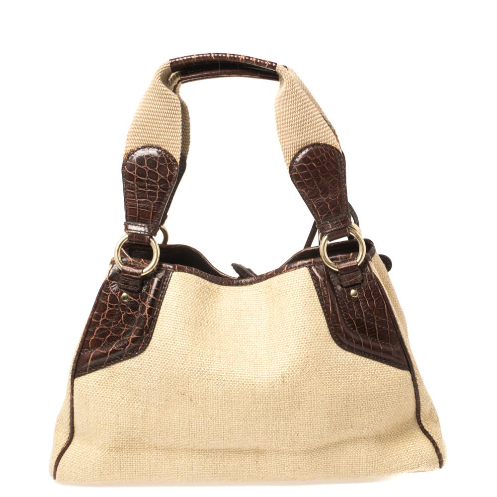 Ideal for everyday use, this Boogie tote is a Celine design. It is crafted from canvas and croc-embossed leather and equipped with a spacious fabric interior housing multiple pockets. The lovely bag is complete with two handles for you to