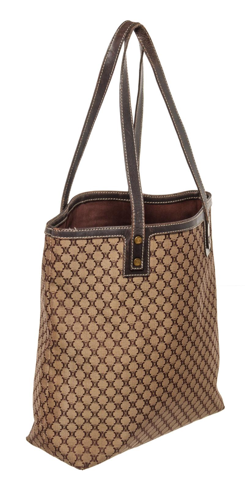 Brown and beige canvas Celine Macadam tote bag with gold-tone hardware, protective feet at base, dual flat handles, brown leather trim, an open top, brown canvas lining, one zip pocket and one slip pocket inside.


46645MSC