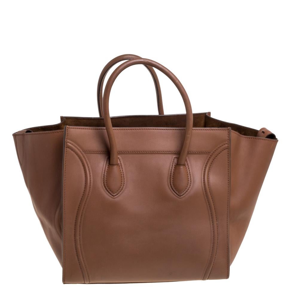 Celine released the Phantom as a newer version of their successful Luggage model. Unlike the Luggage toes, the Phantom has an open-top, wider wingspans, and a braided zipper pull. We have this one in leather. It has two top handles, a lovely brown