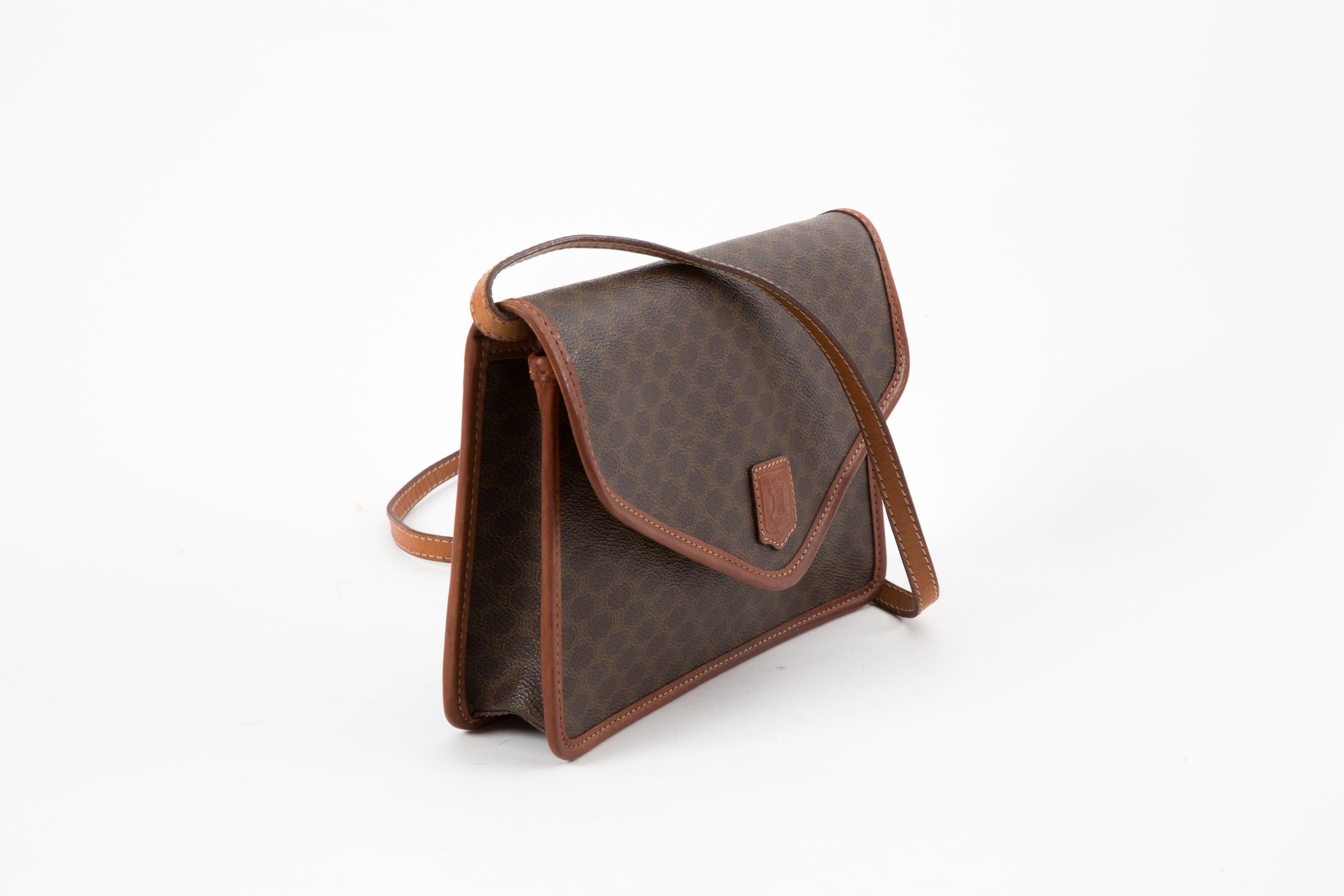 Celine Brown “Macadam” monogram shoulder bag featuring brown “Macadam” monogram canvas with brown leather trim, gold tone hardware with front snap button closure, detachable shoulder/crossbody strap (46,85in. (119cm)), inside zipper pocket, and
