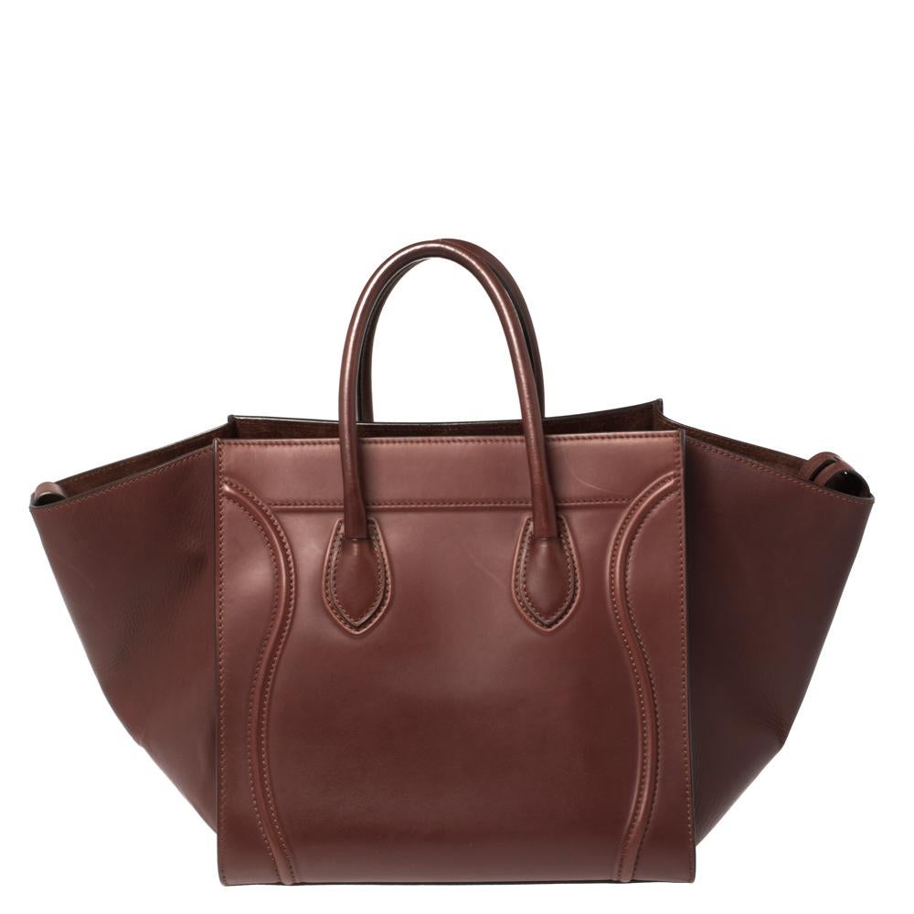 Celine released the Phantom as a newer version of its successful Luggage model. Unlike the Luggage toes, the Phantom has an open-top, wider wingspans, and a braided zipper pull. We have here the one in leather. It has two top handles, a burgundy