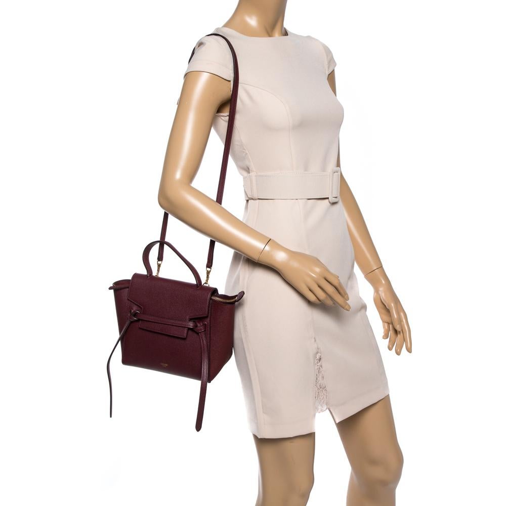 Bags from Celine are symbols of excellent craftsmanship and timeless design. This burgundy creation has been crafted from leather and styled with a front tuck-in flap and belt details. It flaunts a single top handle and a spacious suede interior