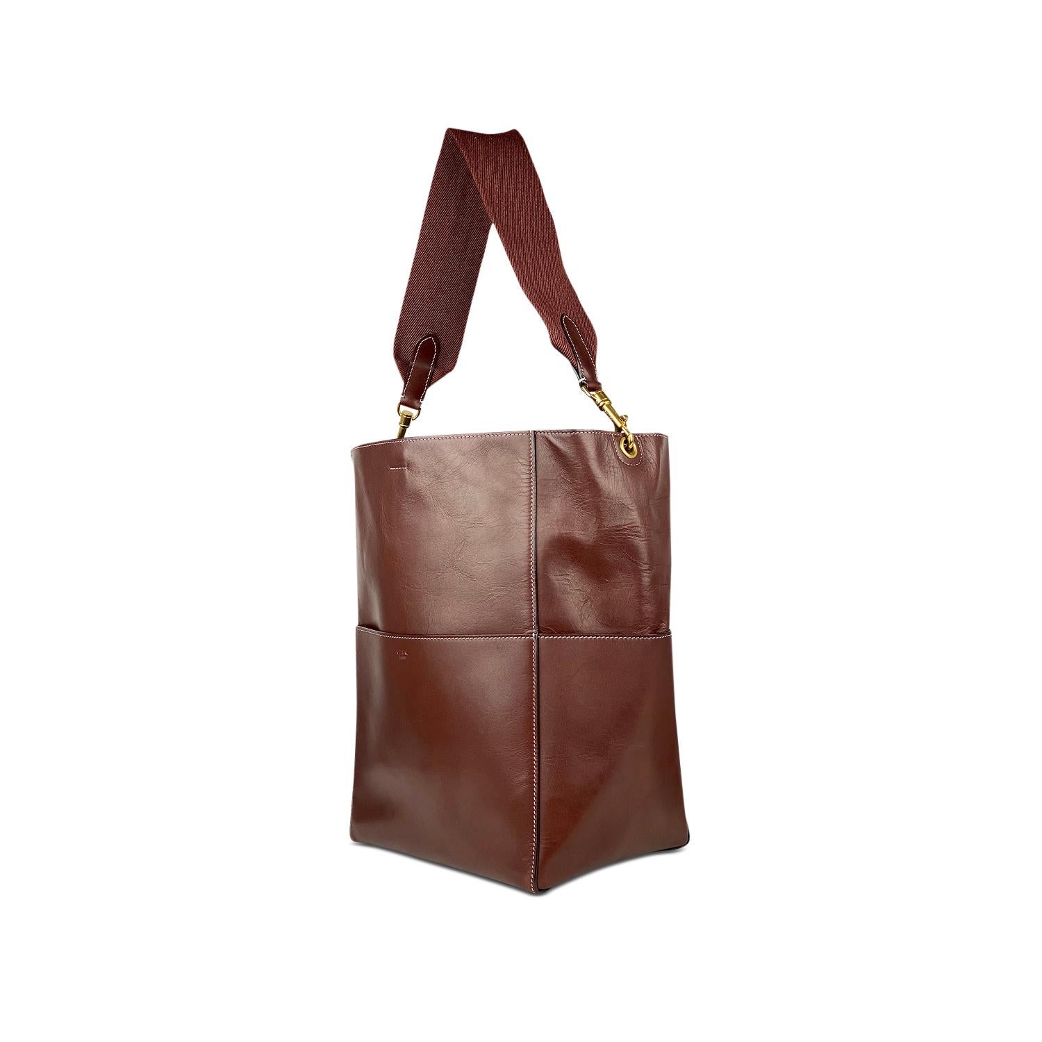 Burgundy calfskin Céline Seau Sangle bag with

- Gold-tone hardware
- Single detachable flat canvas shoulder strap
- Four exterior slit pockets
- Tonal suede lining, dual interior pockets; one with zip closure and hook closure at top

Overall