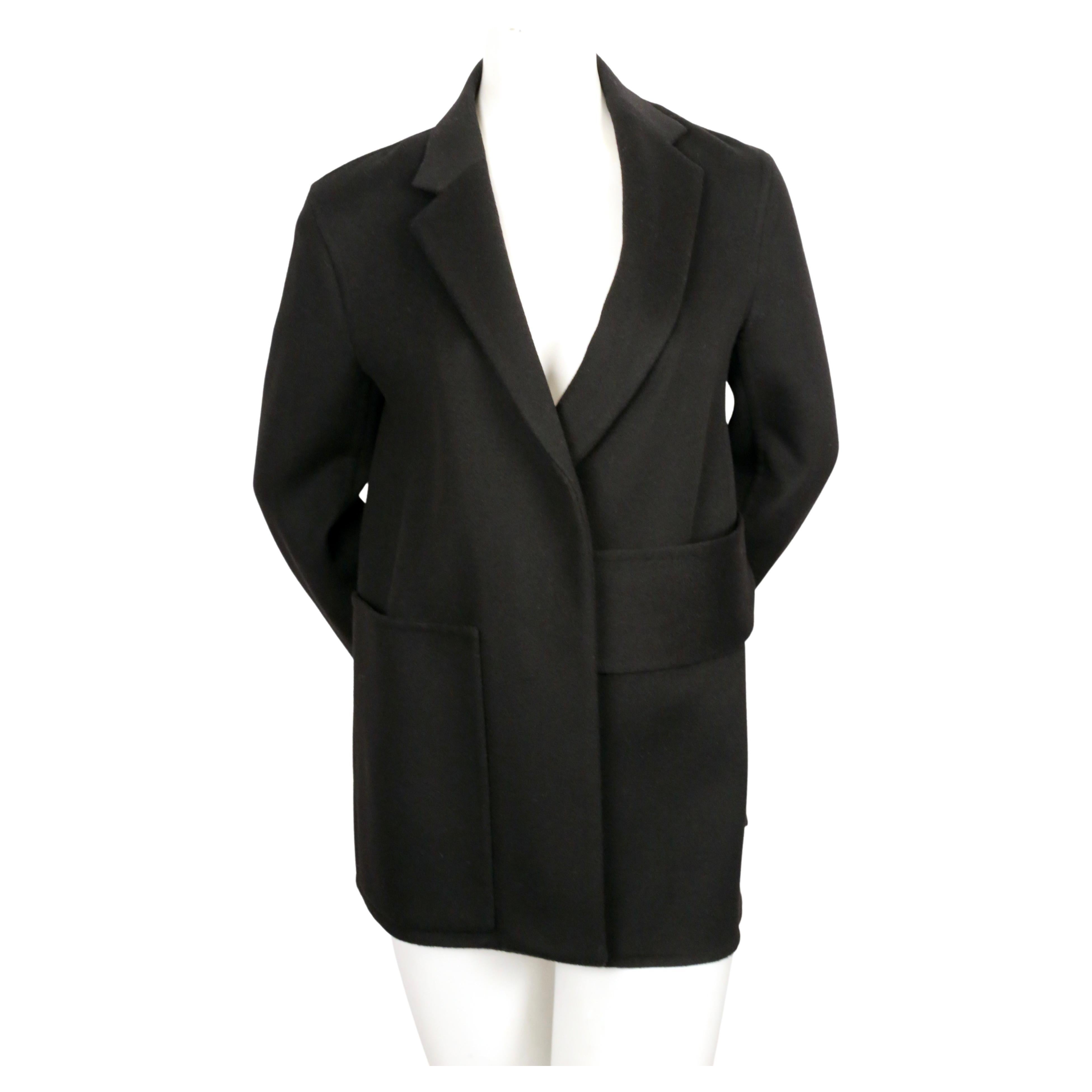 Black double-faced wool and cashmere jacket with wrap around asymmetrical belt  and single patch pocket designed by Phoebe Philo for Celine. French size 40. Approximate measurements: shoulder 16
