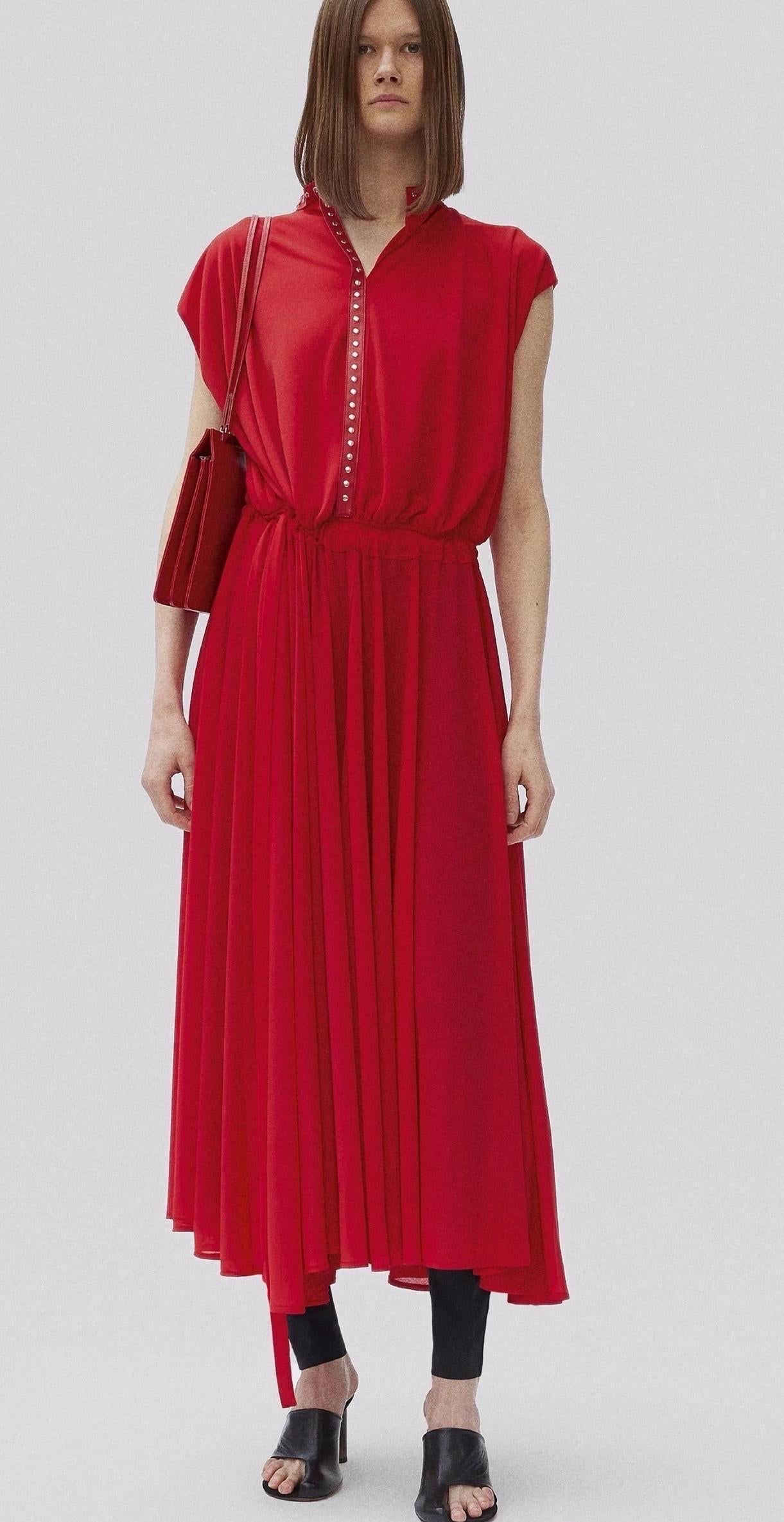 Robe maxi collector de l'époque Old Celine - Collection Pre-Fall 2017 de Phoebe Philo.
Réalisée en crêpe rouge fluide, cette pièce remarquable présente un col en cuir d'agneau clouté et des manches capuchon. Les rubans auto-noués à la taille offrent