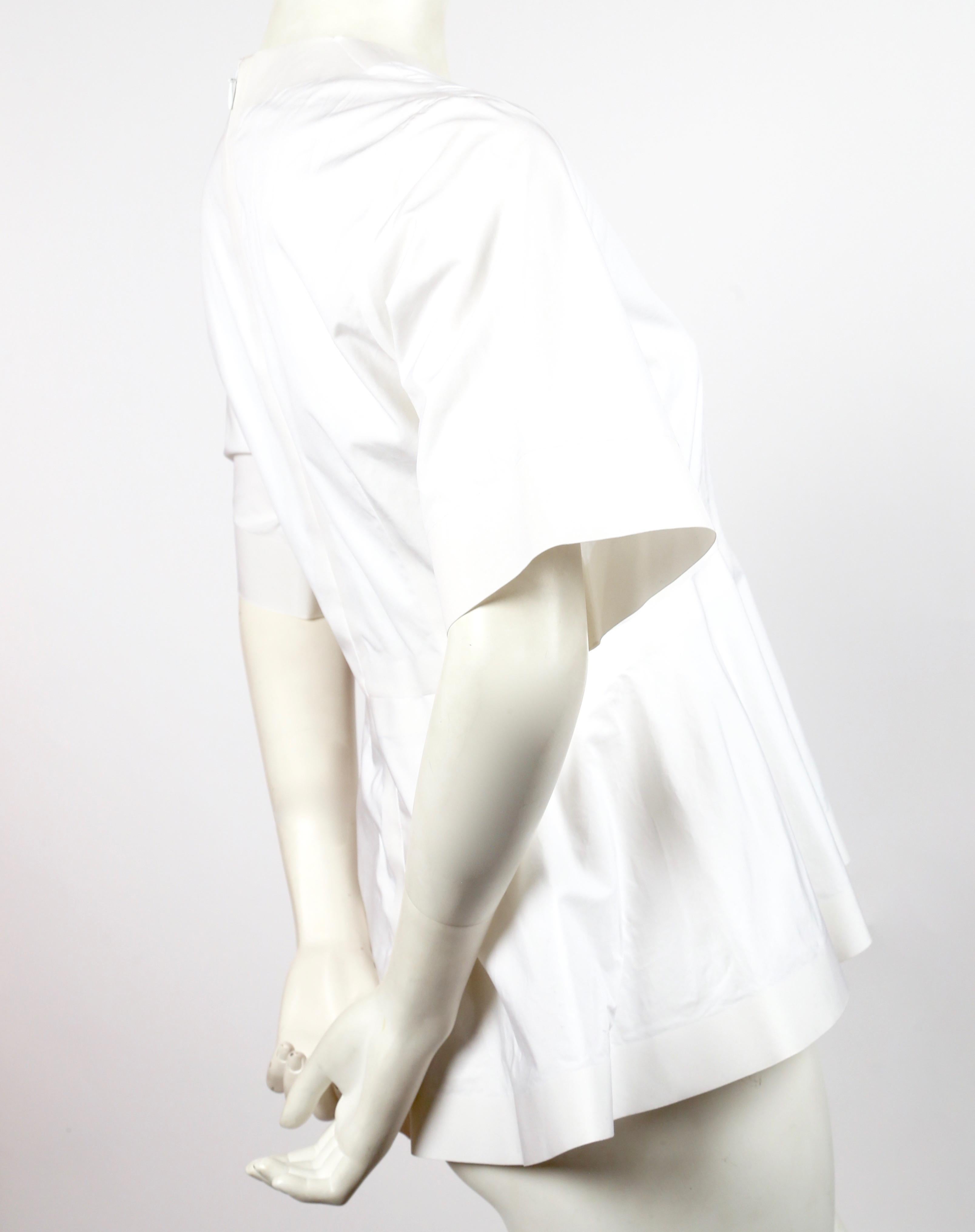 White cotton shirt with crew neck, short sleeves, raw-edge trim and peplum waist designed by Phoebe Philo for Celine exactly as seen on the spring 2012 runway. Labeled a French size 38. Approximate measurements: shoulder 15