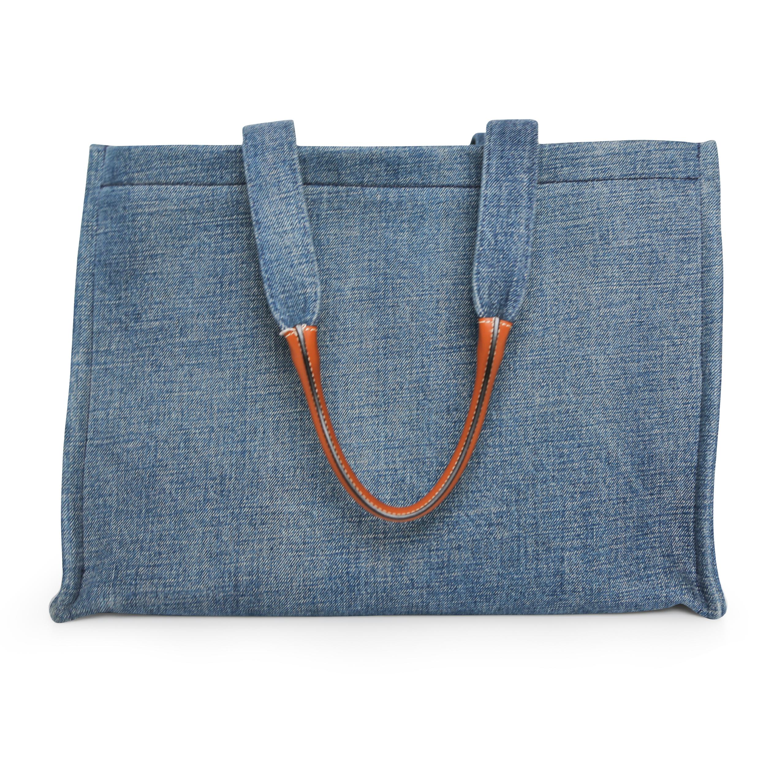 Introducing the Cabas Horizontal Tote, the perfect blend of style and functionality. Crafted with a blue denim exterior, this tote features an eye-catching ivory and blue knit logo patch, and camel leather trim. With a spacious interior and a
