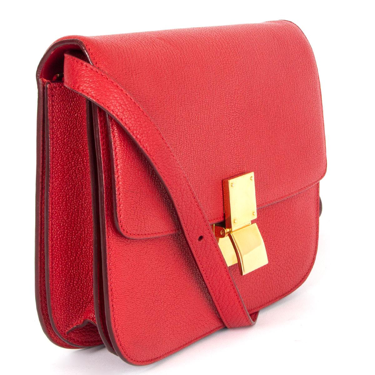 100% authentic Céline Classic Medium shoulder bag in Carmin red goatskin featuring gold-tone hardware. Opens with a push-lock on the front. The inside is divided into two compartments with two open pockets against the front and a zipper pocket