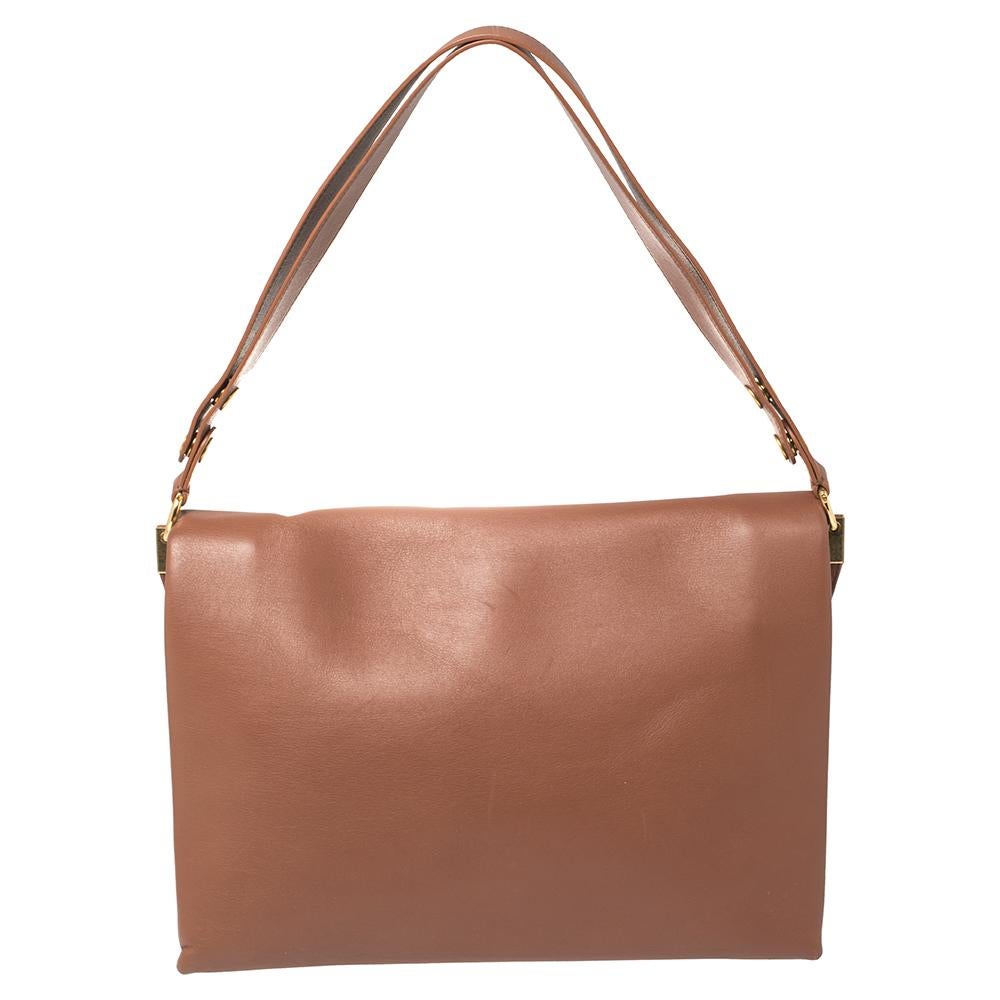 Carry along a mark of sophistication with this simple yet attractive Celine bag. It has been crafted in leather in the cinnamon shade. The bag features a top handle and flap closure with gold-tone detailing. The interior has two open compartments