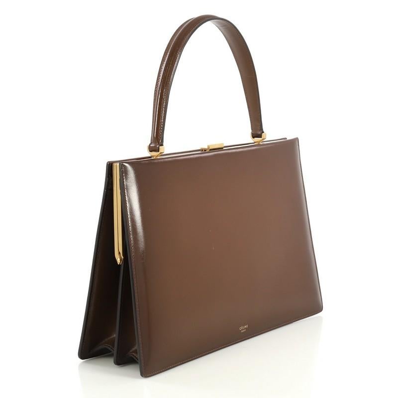 This Celine Clasp Top Handle Bag Leather Medium, crafted in brown leather, features a leather top handle, stamped Celine logo, framed top, and aged gold-tone hardware. Its clasp closure opens to an orange leather interior divided into two